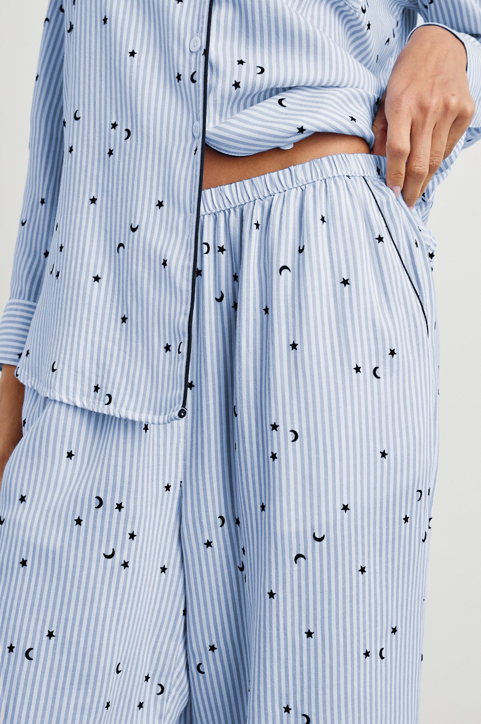 Luna Pajama Set with a Long Sleeve, Button Up, V Neck Top with a Chest Patch Pocket and Pants with Two Front Pockets in Flocked Cosmic Stripe Colorway, Black Moons and Stars on Blue and White Vertical Stripe - Front View Featured on Model
