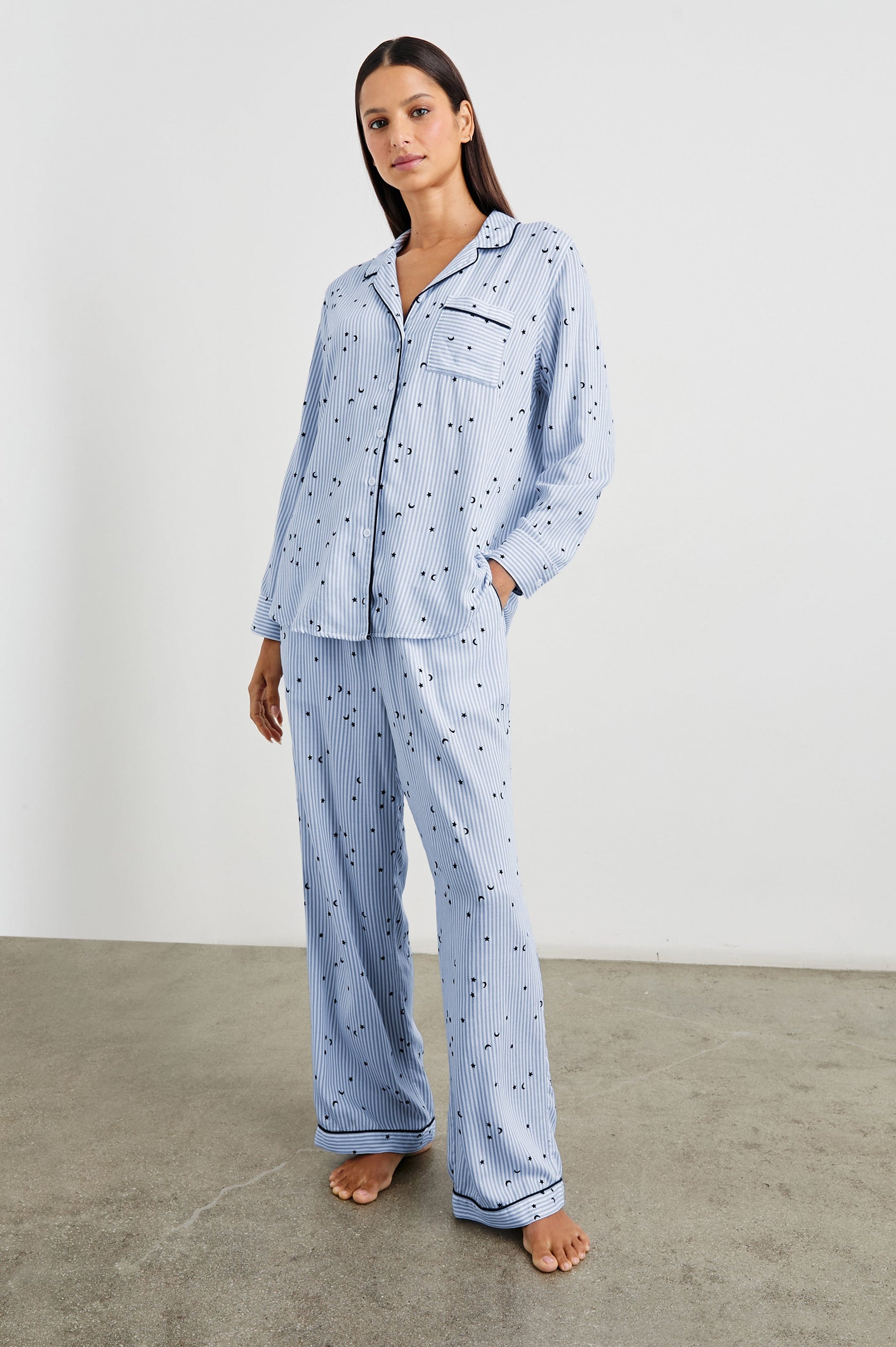 Luna Pajama Set with a Long Sleeve, Button Up, V Neck Top with a Chest Patch Pocket and Pants with Two Front Pockets in Flocked Cosmic Stripe Colorway, Black Moons and Stars on Blue and White Vertical Stripe - Front Full Body View Featured on Model