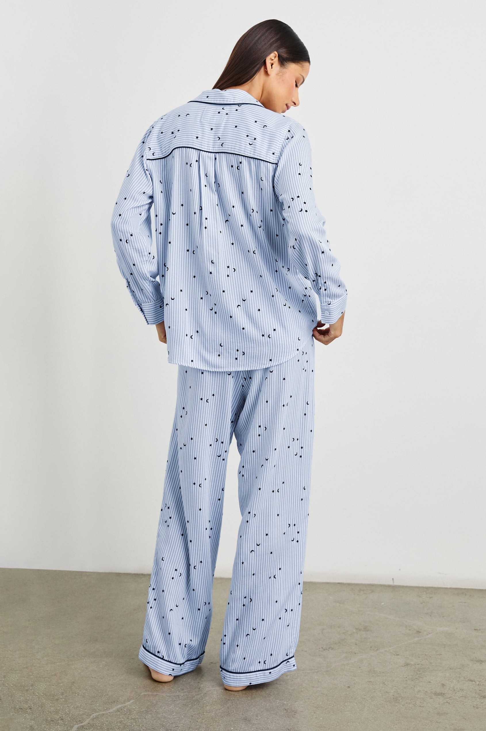 Luna Pajama Set with a Long Sleeve, Button Up, V Neck Top with a Chest Patch Pocket and Pants with Two Front Pockets in Flocked Cosmic Stripe Colorway, Black Moons and Stars on Blue and White Vertical Stripe - Back Full Body View Featured on Model