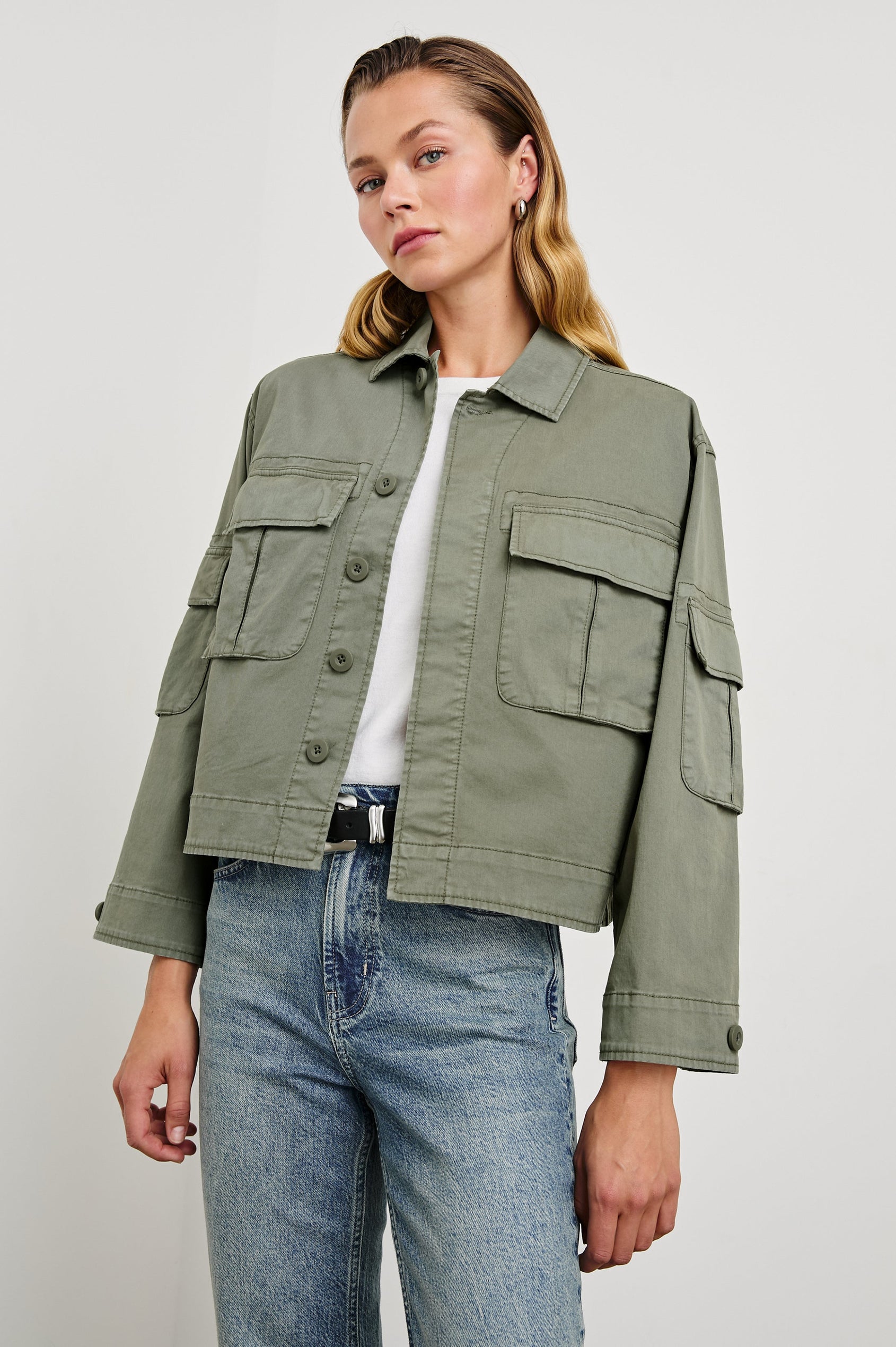Madison Jacket with Button Closure, Two Chest Flap Pockets, Two Sleeve Flap Pockets, Adjustable Button Tab at Cuffs, and a Button Tab at Hem in Dark Olive Colorway - Front View Featured on Model