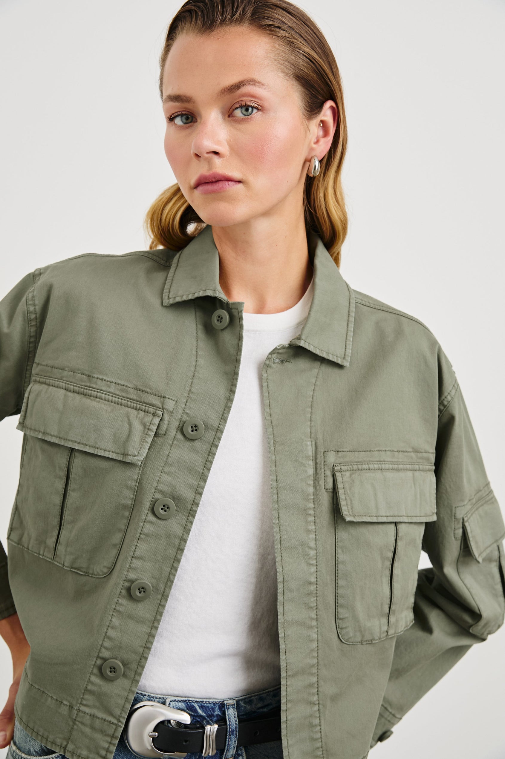 Madison Jacket with Button Closure, Two Chest Flap Pockets, Two Sleeve Flap Pockets, Adjustable Button Tab at Cuffs, and a Button Tab at Hem in Dark Olive Colorway - Front View Featured on Model