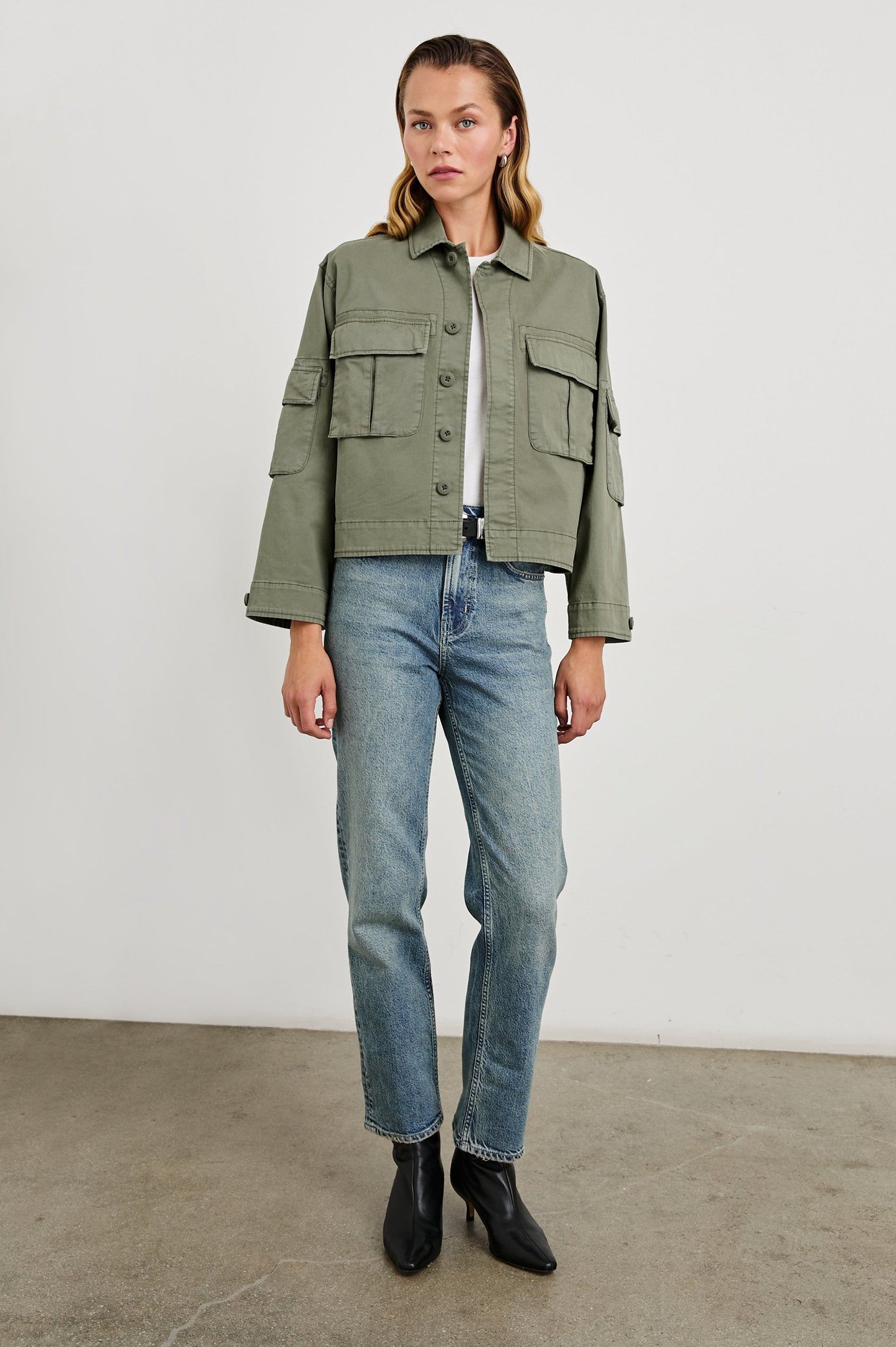 Madison Jacket with Button Closure, Two Chest Flap Pockets, Two Sleeve Flap Pockets, Adjustable Button Tab at Cuffs, and a Button Tab at Hem in Dark Olive Colorway - Front Full Body View Featured on Model