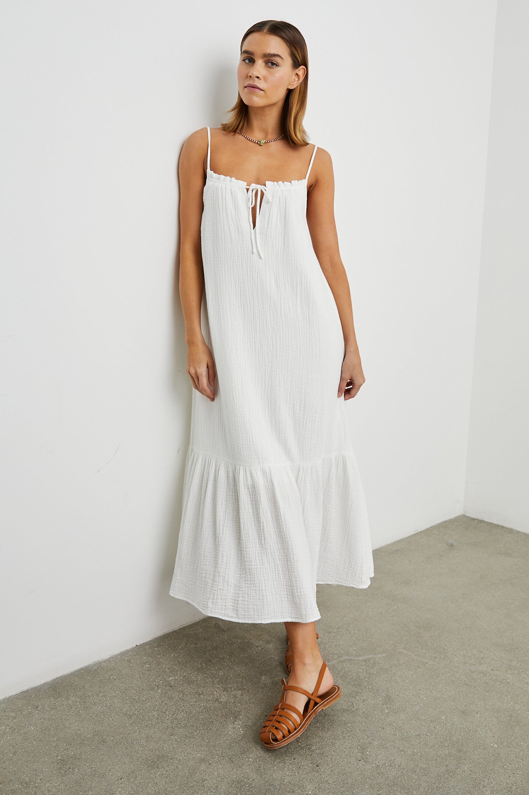 Marseille Midi Dress with Adjustable Spaghetti Straps, a Deep V Neck with a Tie, and a Lightly Ruffled Hem in White Colorway - Front Full Body View Featured on Model