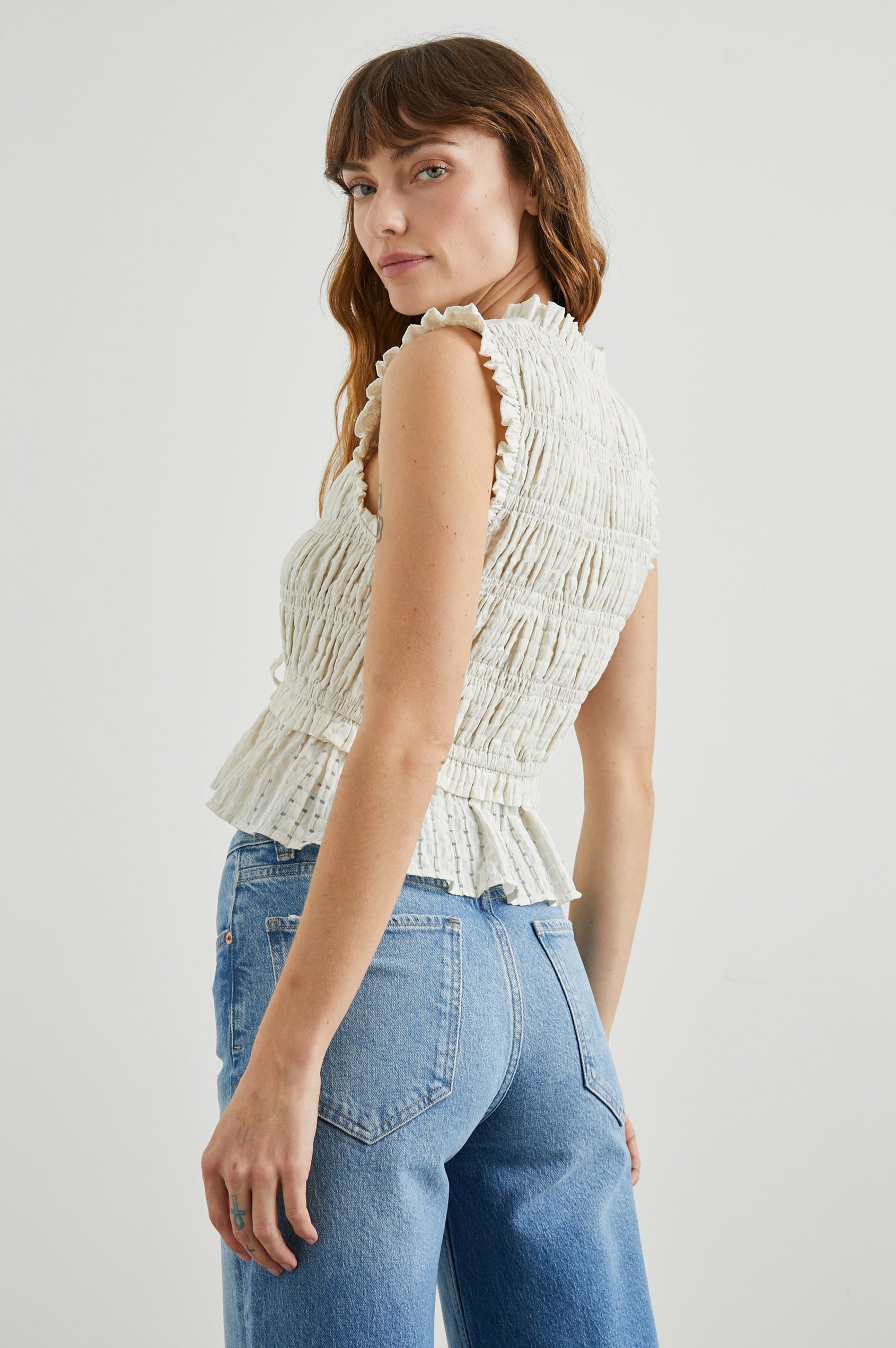 Martine Sleeveless Top with Ruffled Trim, a Deep V-Neck with Ties and Smocking in Ivory Seersucker Colorway - Back View Featured on Model