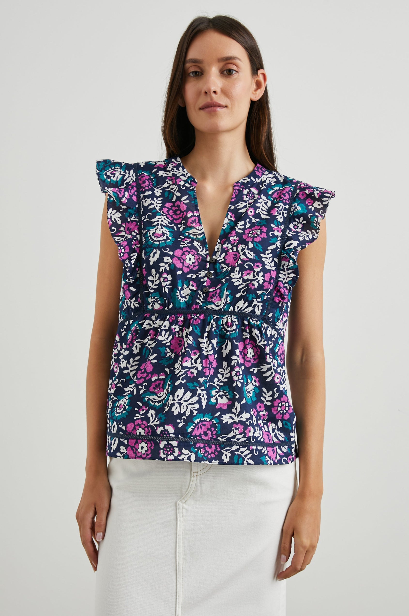 Misha Short Sleeve Top with Flutter Sleeves, a Deep V Neck, and Vertical and Horizontal Black Seams in Woodblock Floral Colorway, Pink, White and Green on Navy - Front View Featured on Model