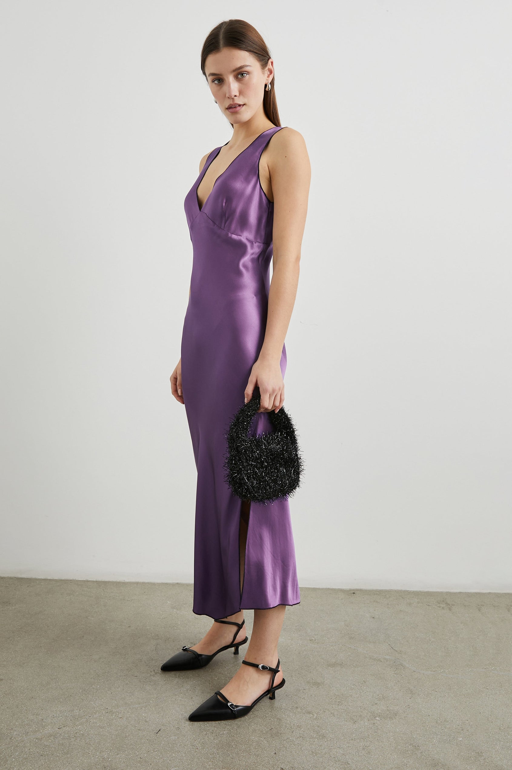 Monique Sleeveless Midi Dress with an Asymmetrical Hem Line, Side Slit, Deep V Neck, and Wide Shoulder Straps in Amethyst Colorway - Side Full Body View Featured on Model