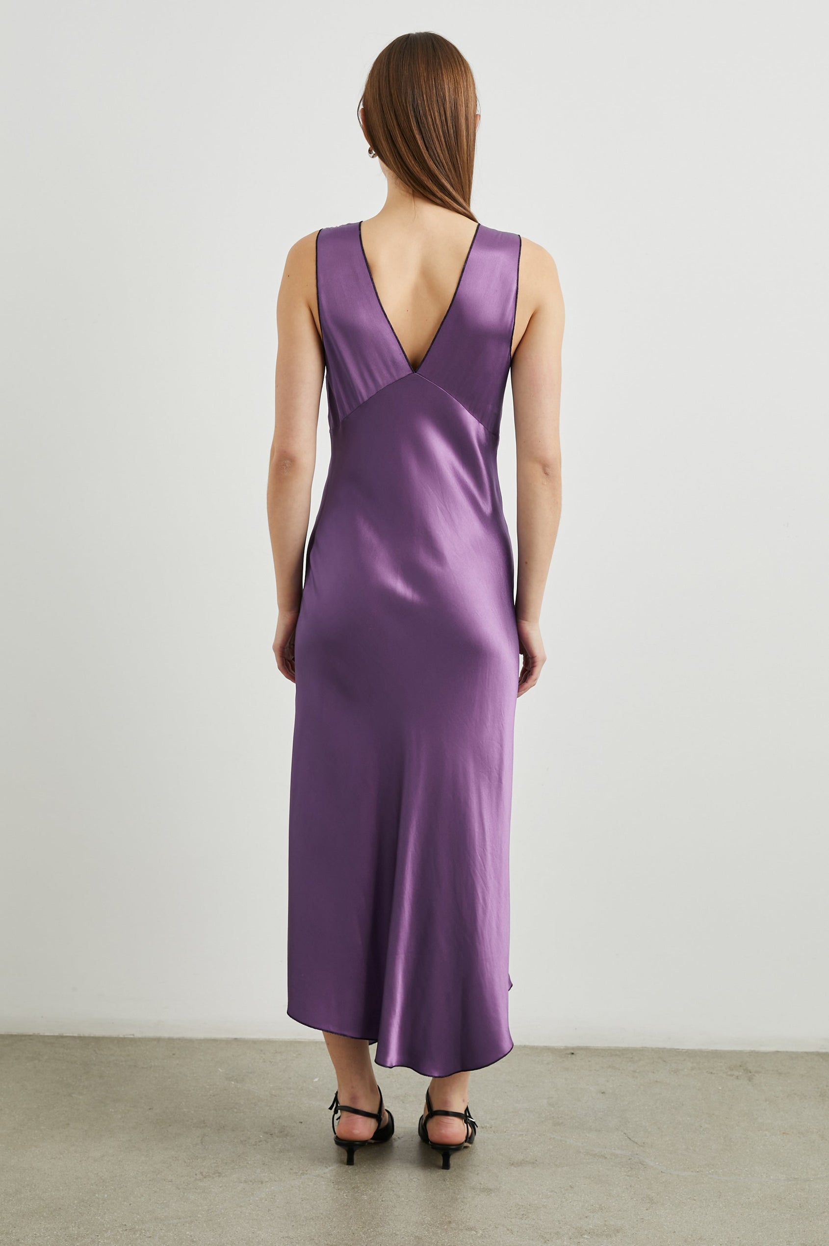 Monique Sleeveless Midi Dress with an Asymmetrical Hem Line, Side Slit, Deep V Neck, and Wide Shoulder Straps in Amethyst Colorway - Back Full Body View Featured on Model