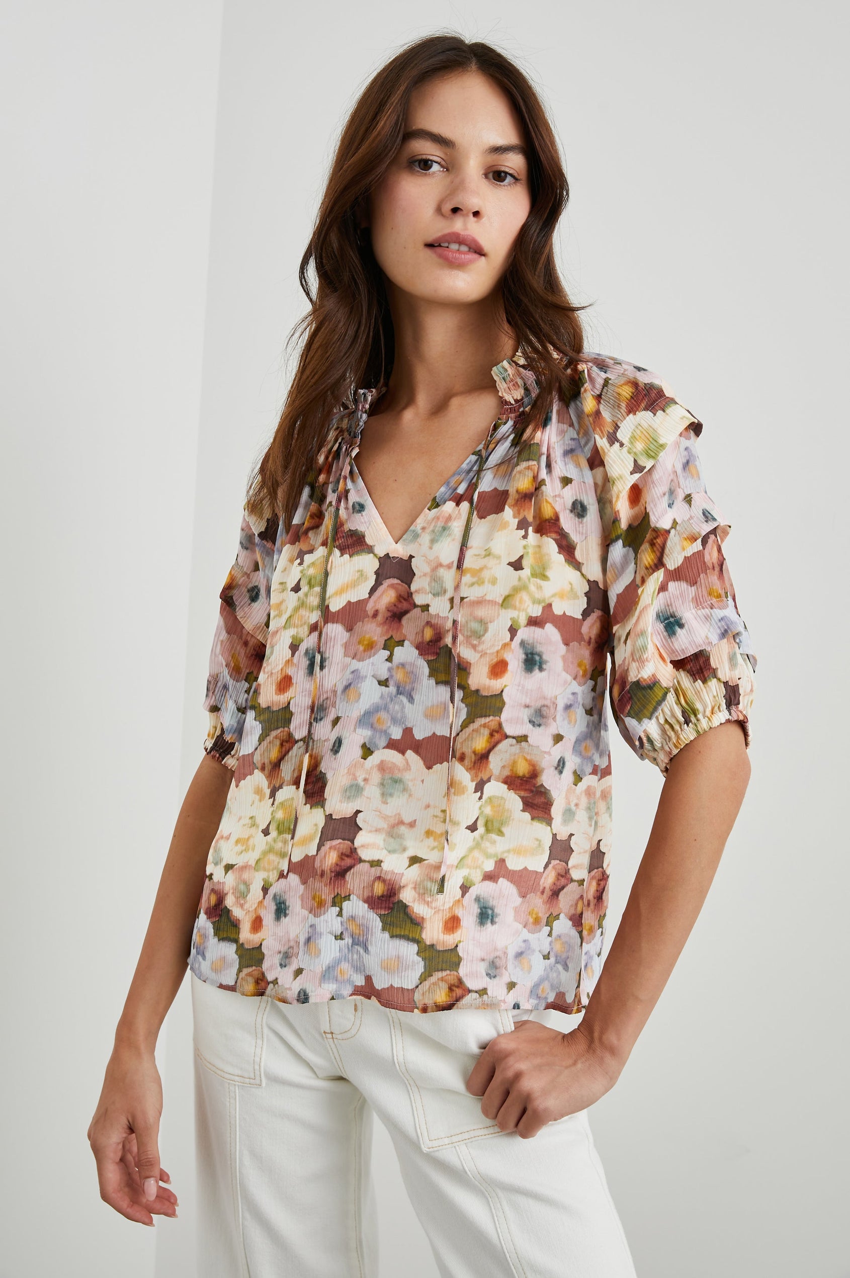 Paris Short-Sleeve Top with Shirred Collar, V-neckline with Ties, Deep Pleats on Sleeves and Elastic at the Sleeve Opening in Painted Floral Colorway, with browns, yellows, and blues - Front untucked View Featured on Model