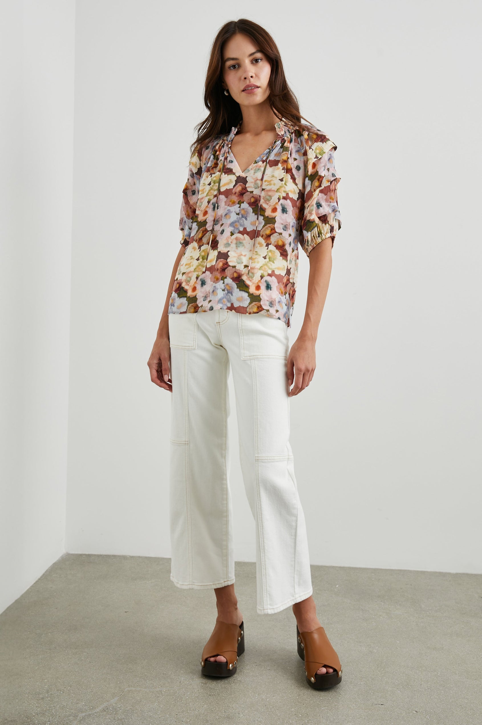 Paris Short-Sleeve Top with Shirred Collar, V-neckline with Ties, Deep Pleats on Sleeves and Elastic at the Sleeve Opening in Painted Floral Colorway, with browns, yellows, and blues - Front untucked Full Body View Featured on Model