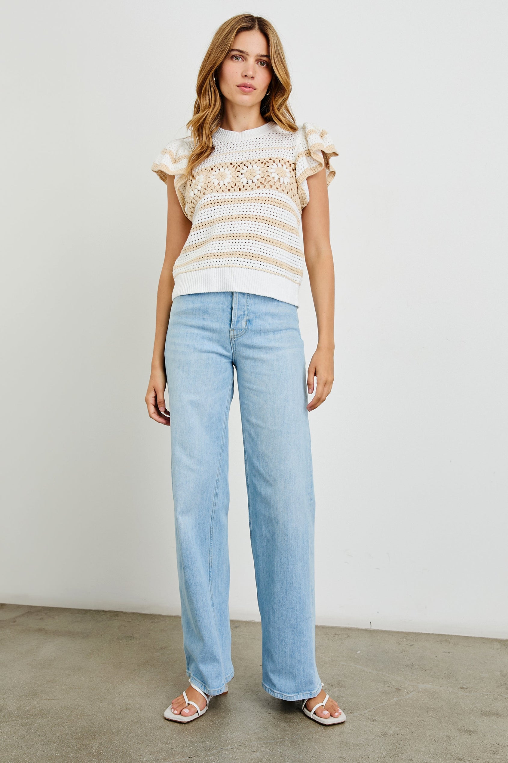 Penelope Crochet Top with Flutter Sleeves and Ribbed Hem in Ivory Oat Crochet Stripe Colorway, with contrasting knit flowers across the chest - Front Full Body View Featured on Model