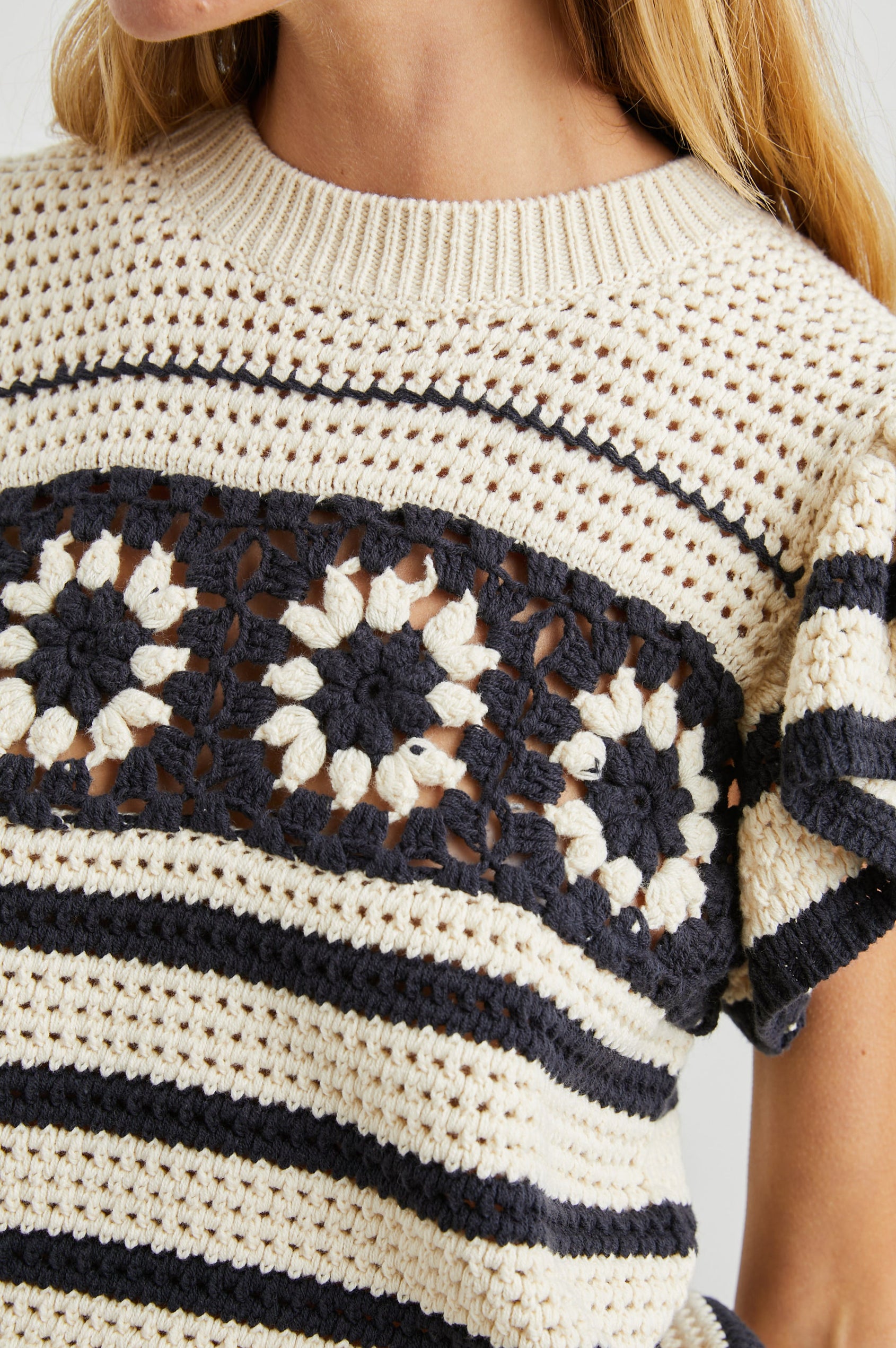 Penelope Crochet Top with Flutter Sleeves and Ribbed Hem in Oat Navy Crochet Colorway, Horizontal Stripes with contrasting knit flowers across the chest - Front View Featured on Model