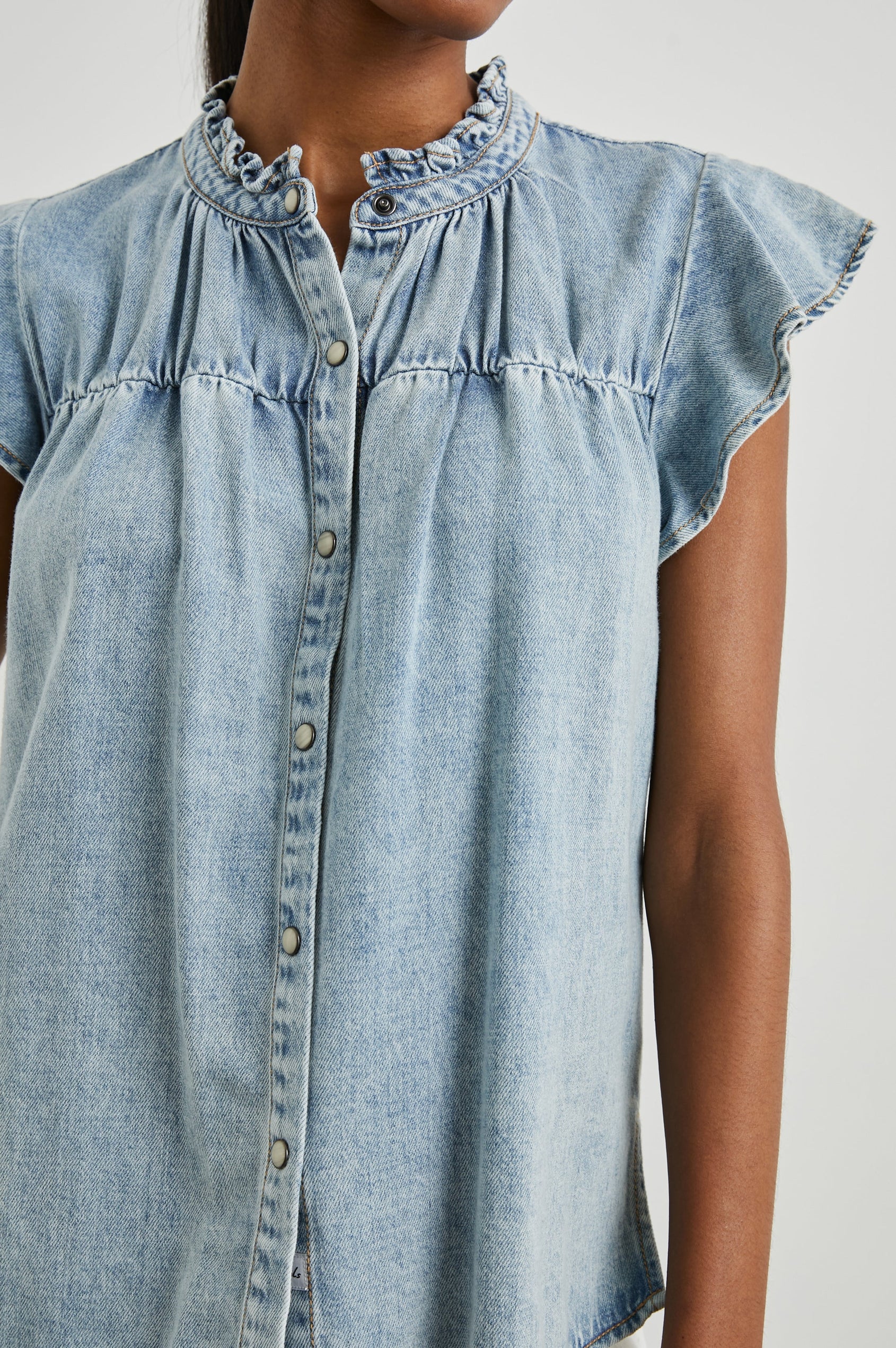 Ruthie Top with Flutter Cap Sleeves, a Ruffled Banded Collar, Buttons Down the Front, and Soft Shirring at Front Yoke in Faded Indigo Colorway - Front View Featured on Model