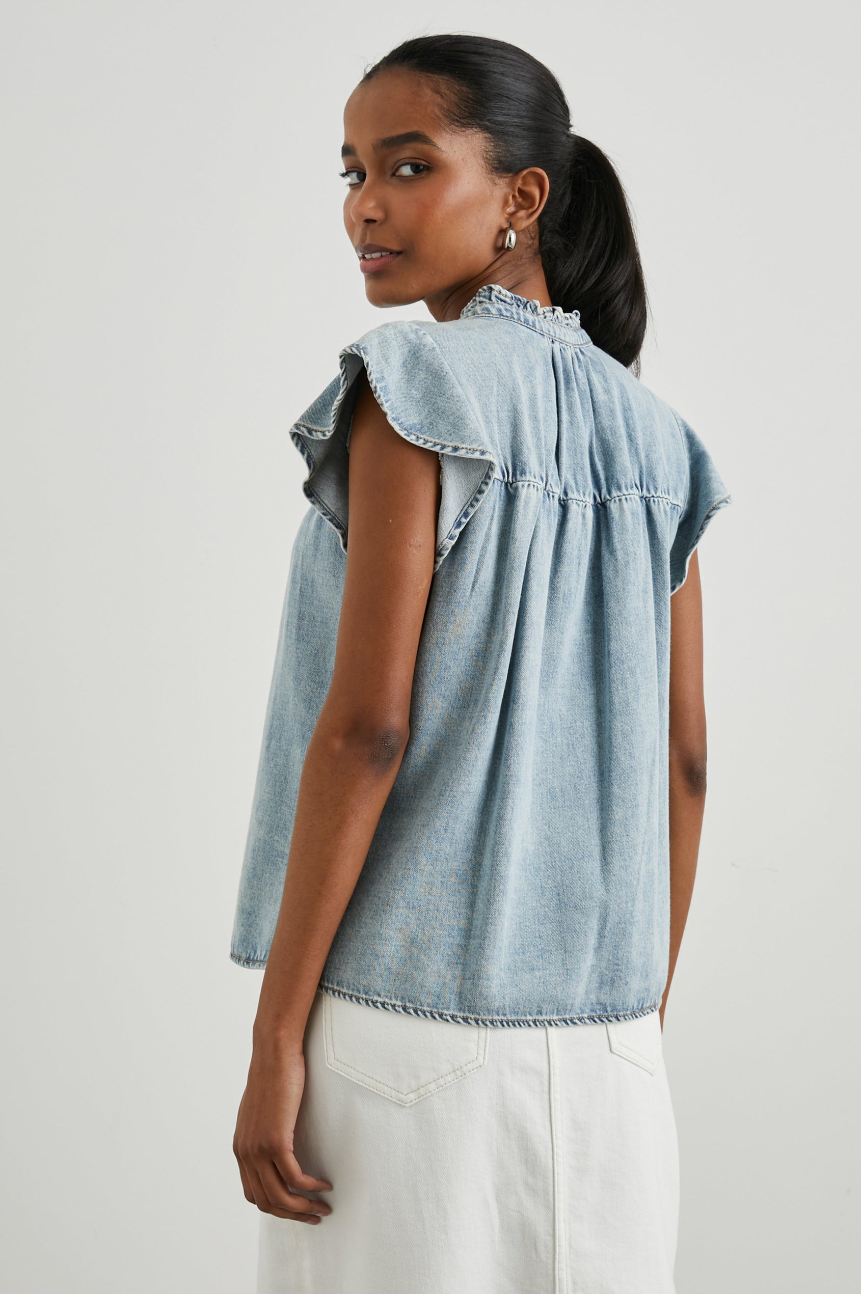 Ruthie Top with Flutter Cap Sleeves, a Ruffled Banded Collar, Buttons Down the Front, and Soft Shirring at Front Yoke in Faded Indigo Colorway - Back View Featured on Model
