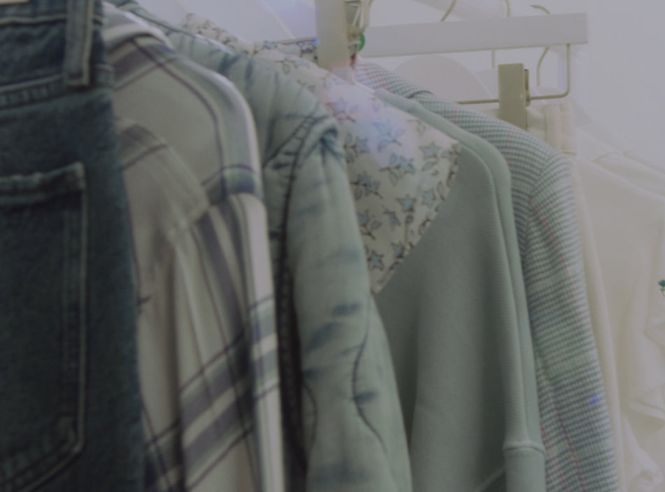 CLOSE UP IMAGE OF MULTIPLE PIECES OF CLOTHING HANGING ON A CLOTHING RACK. ALL OF THE ITEMS OF CLOTHING ARE IN VARIOUS SHADES OF LIGHT BLUE