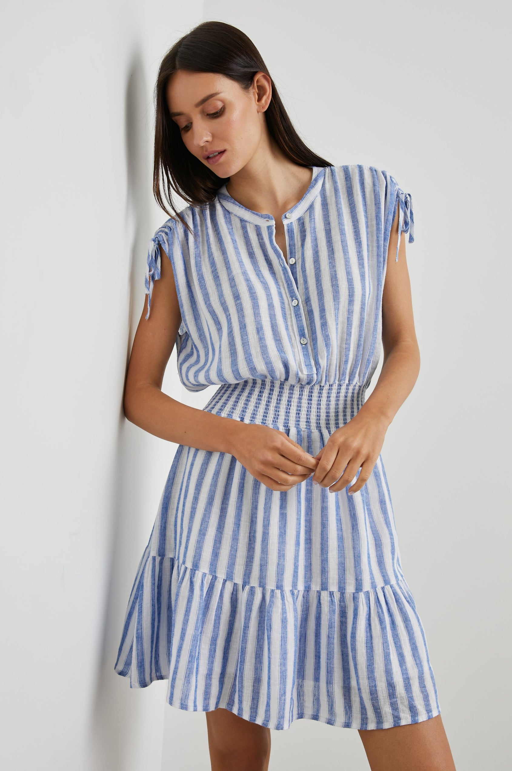 Samina Above-Knee Sleeveless Dress with drawstrings at the Sleeve Openings, Buttons along the Bodice, A Cinched Waist and a Tiered Skirt in Casablanca Stripe Colorway, with blue vertical stripes on white - Front View Featured on Model