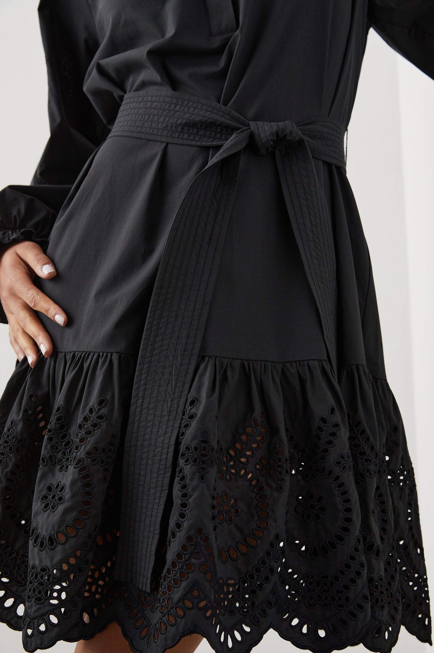 Saylor Long-Sleeve Midi Dress with a Half-Sealed Placket, a V Neck, Ruffled Collar with Shirring, a Fabric Tie Belt, and Floral and Geometric Eyelet Details in Black Eyelet Colorway - Front View Featured on Model