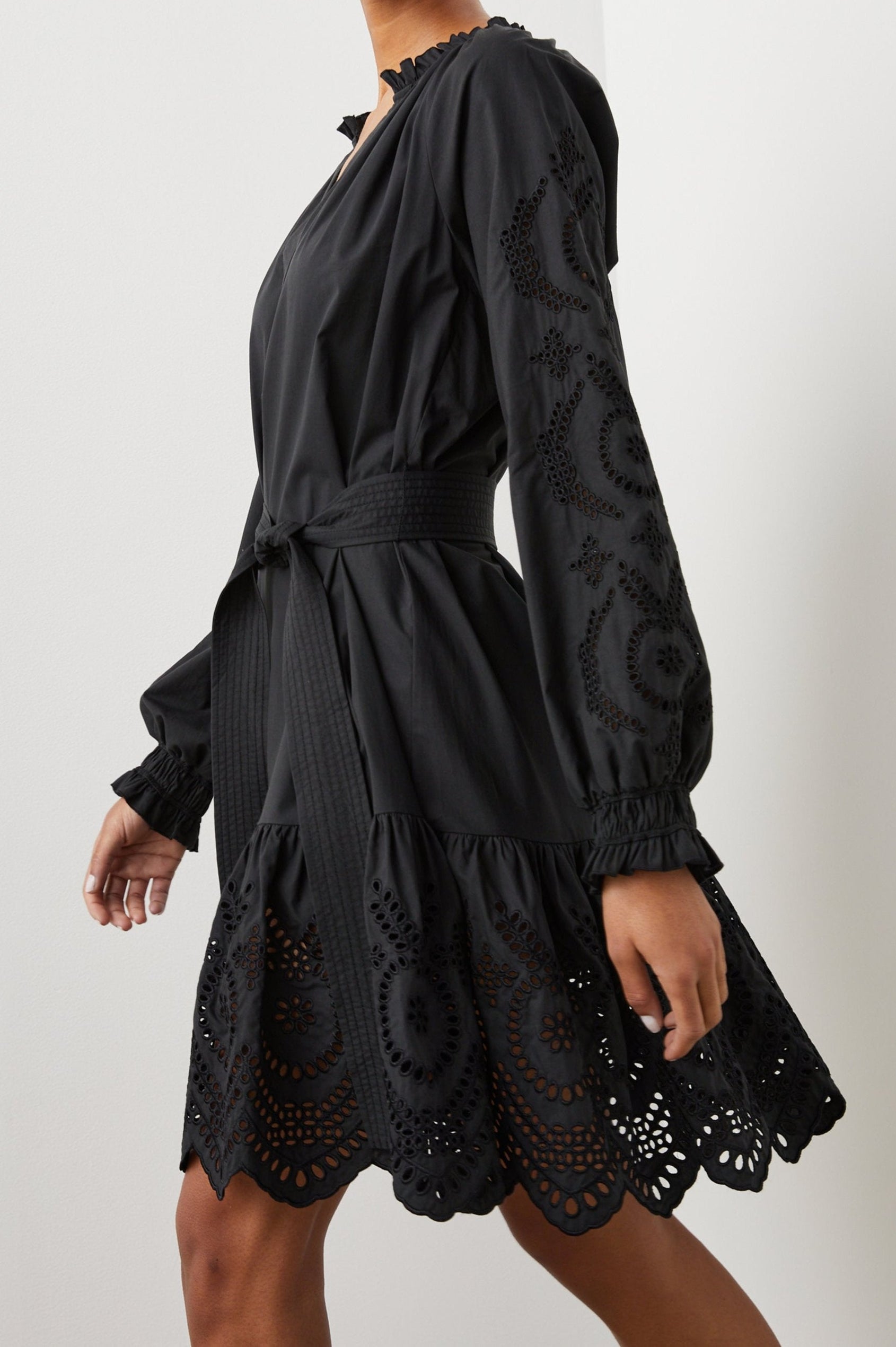 Saylor Long-Sleeve Midi Dress with a Half-Sealed Placket, a V Neck, Ruffled Collar with Shirring, a Fabric Tie Belt, and Floral and Geometric Eyelet Details in Black Eyelet Colorway - Side View Featured on Model