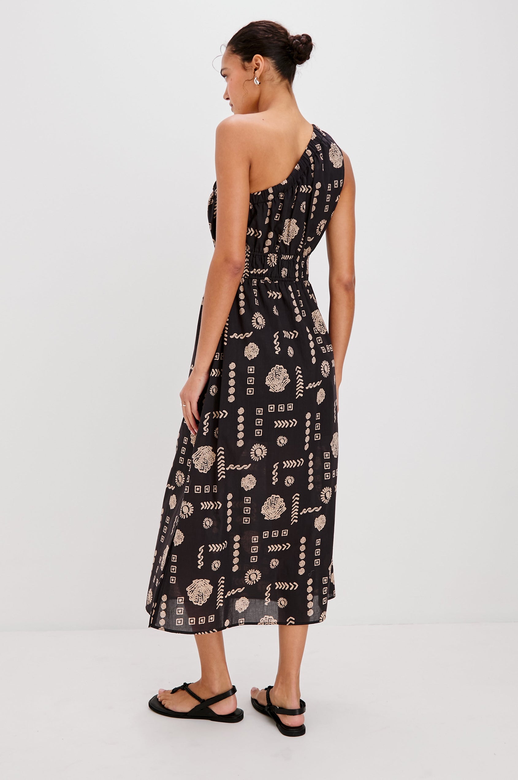 Selani Below-Knee One Shoulder Dress with a Side Slit and Encased Elastic Across Chest and Waist. Full Body Back View Shown on Model.