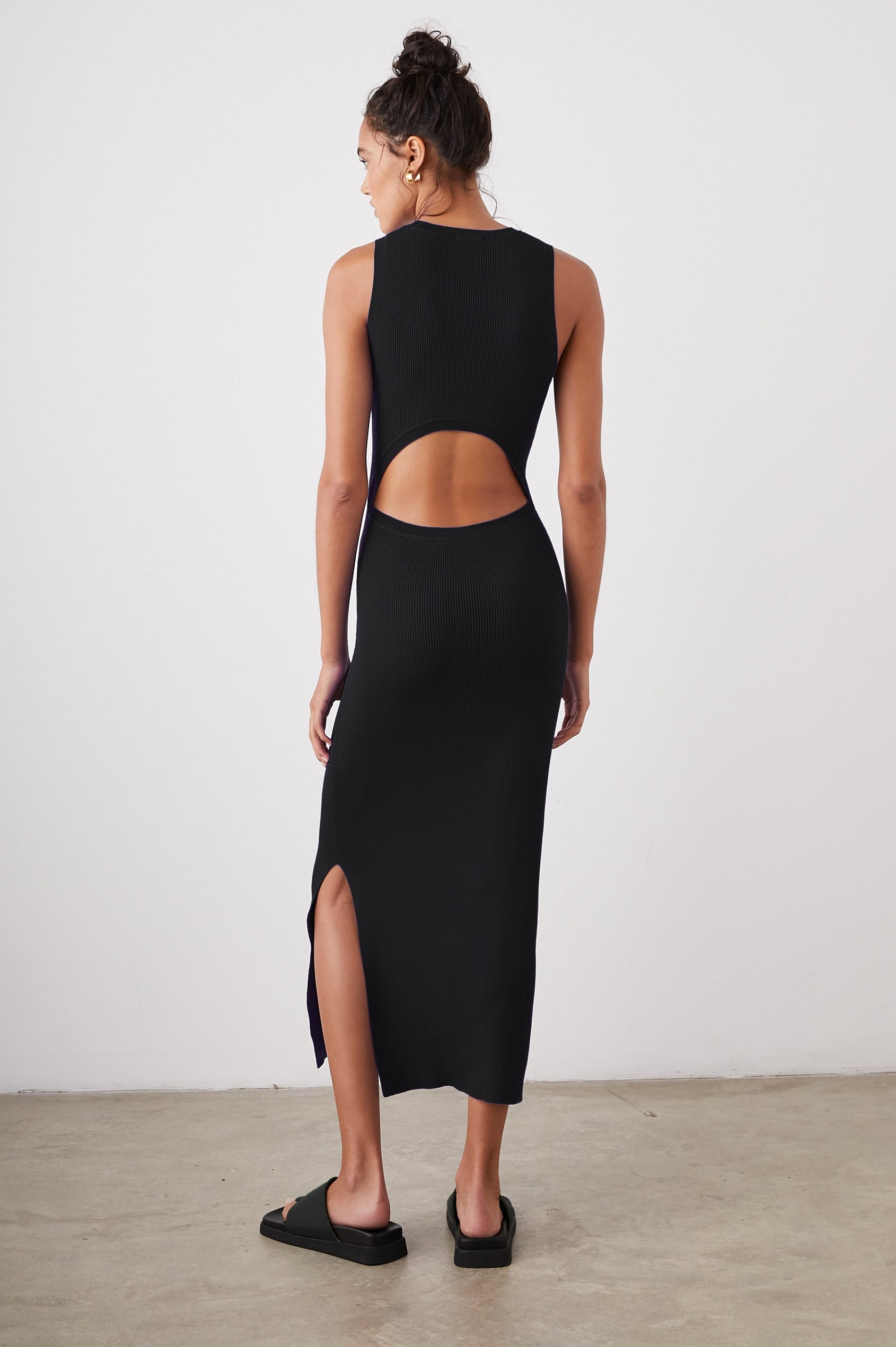 Syd Ribbed, Sleeveless Midi Dress with Wide Shoulder Straps, a Side Slit, and a Cutout that Spans the Lower Back in Black Colorway - Back Full Body View Featured on Model