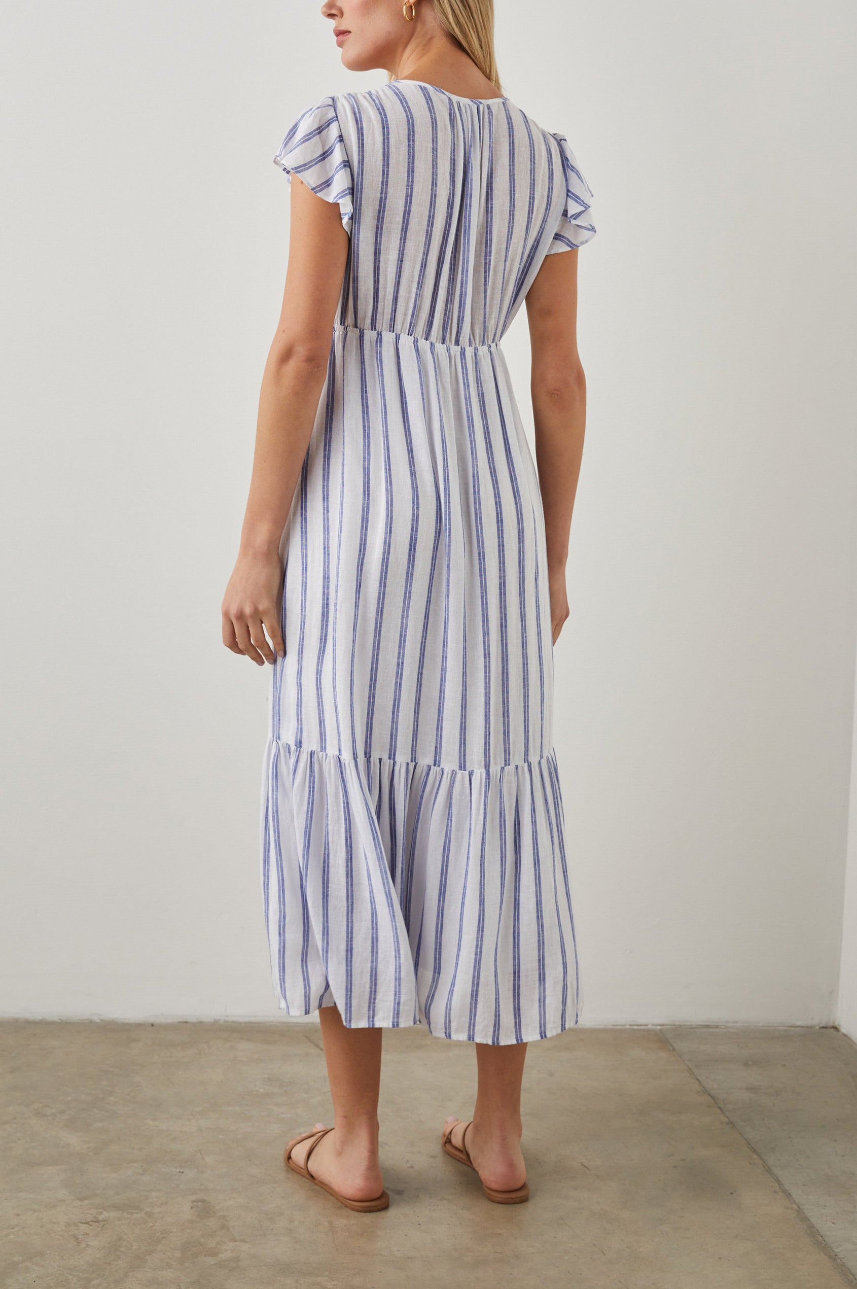 Tina Short Sleeve Midi Dress with Flutter Sleeves, a Deep V Neck with a Cutout and a Tiered Skirt in Villa Stripe Colorway, with Thin Vertical Blue Stripes on White - Back Full Body View Featured on Model