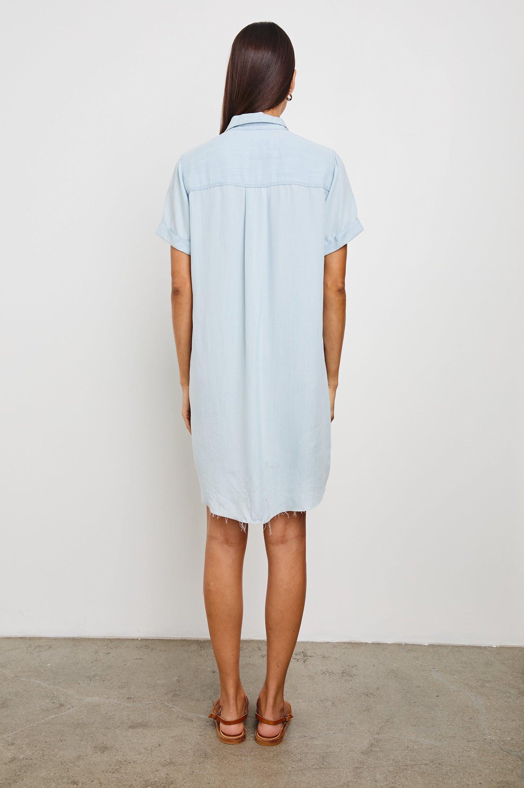 Valerie Short-Sleeve Denim Mini Dress with Rolled Cuffs, a Collar, a Half Sealed Placket, a Chest Pocket and a Raw Hem in Light Vintage Colorway - Back Full Body View Featured on Model