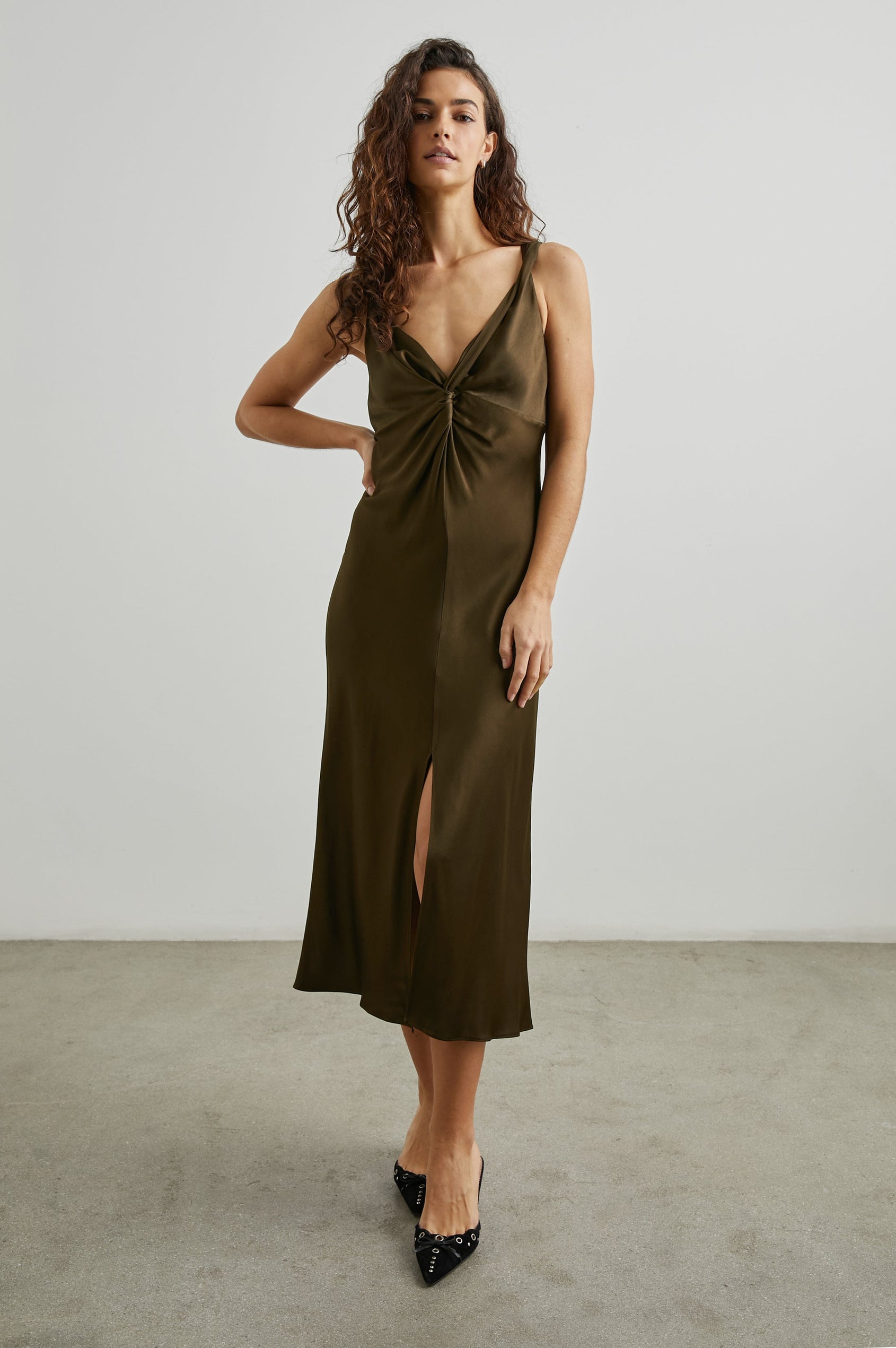Viviana Sleeveless Midi Dress with a Deep V Neck that Extends into a Twist, Twisted Shoulder Straps, and a Center Slit in Dark Moss Colorway - Front Full Body View Featured on Model