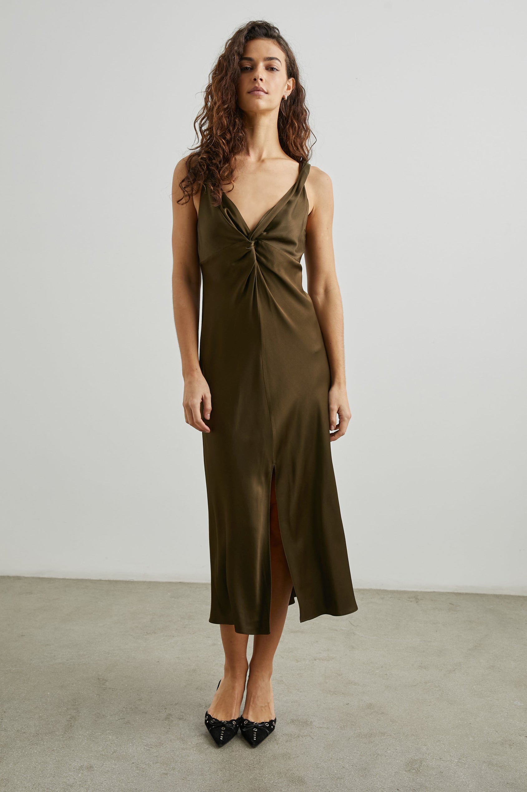 Viviana Sleeveless Midi Dress with a Deep V Neck that Extends into a Twist, Twisted Shoulder Straps, and a Center Slit in Dark Moss Colorway - Front Full Body View Featured on Model