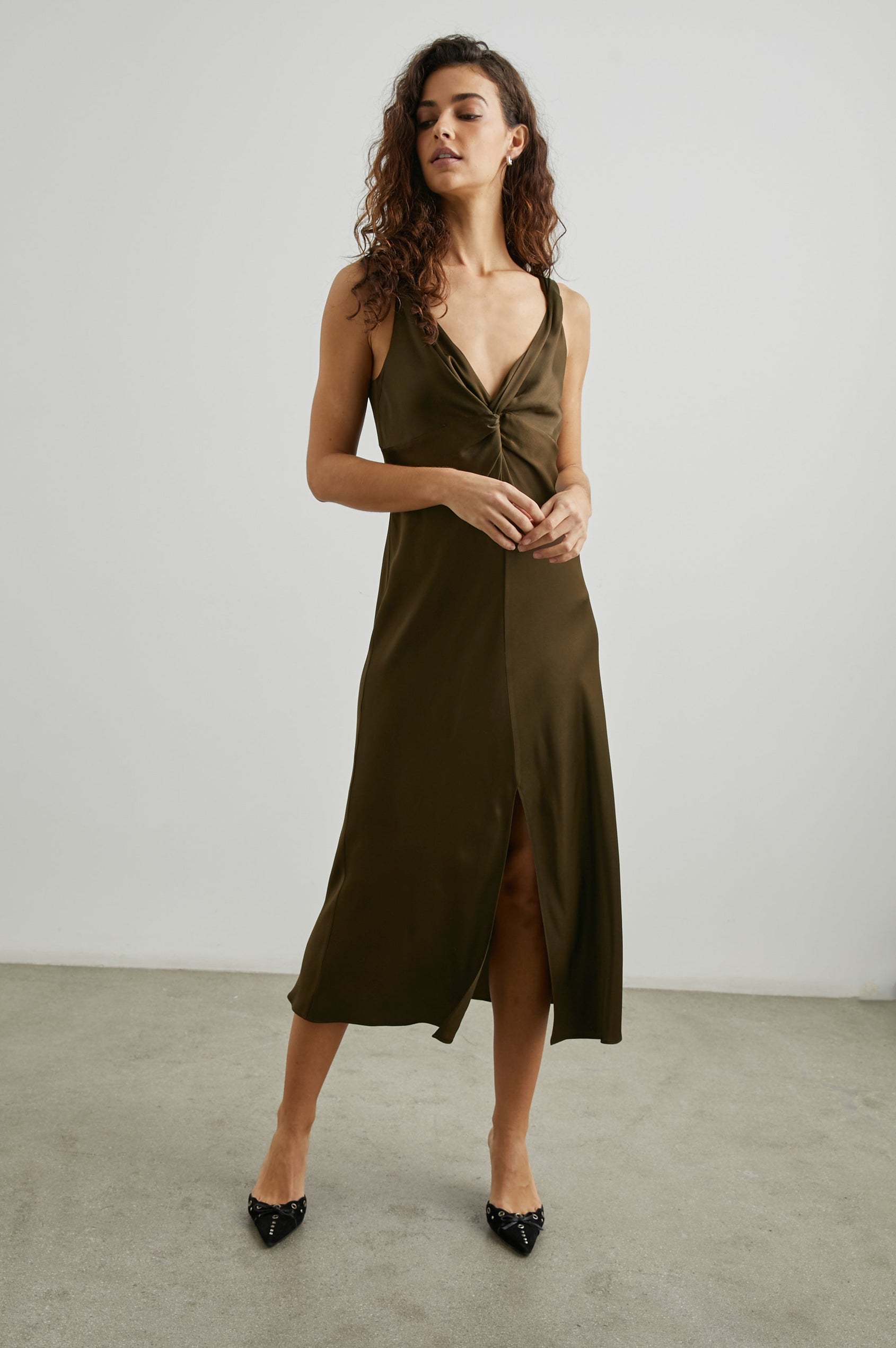 Viviana Sleeveless Midi Dress with a Deep V Neck that Extends into a Twist, Twisted Shoulder Straps, and a Center Slit in Dark Moss Colorway - Front Full Body View Featured on Model