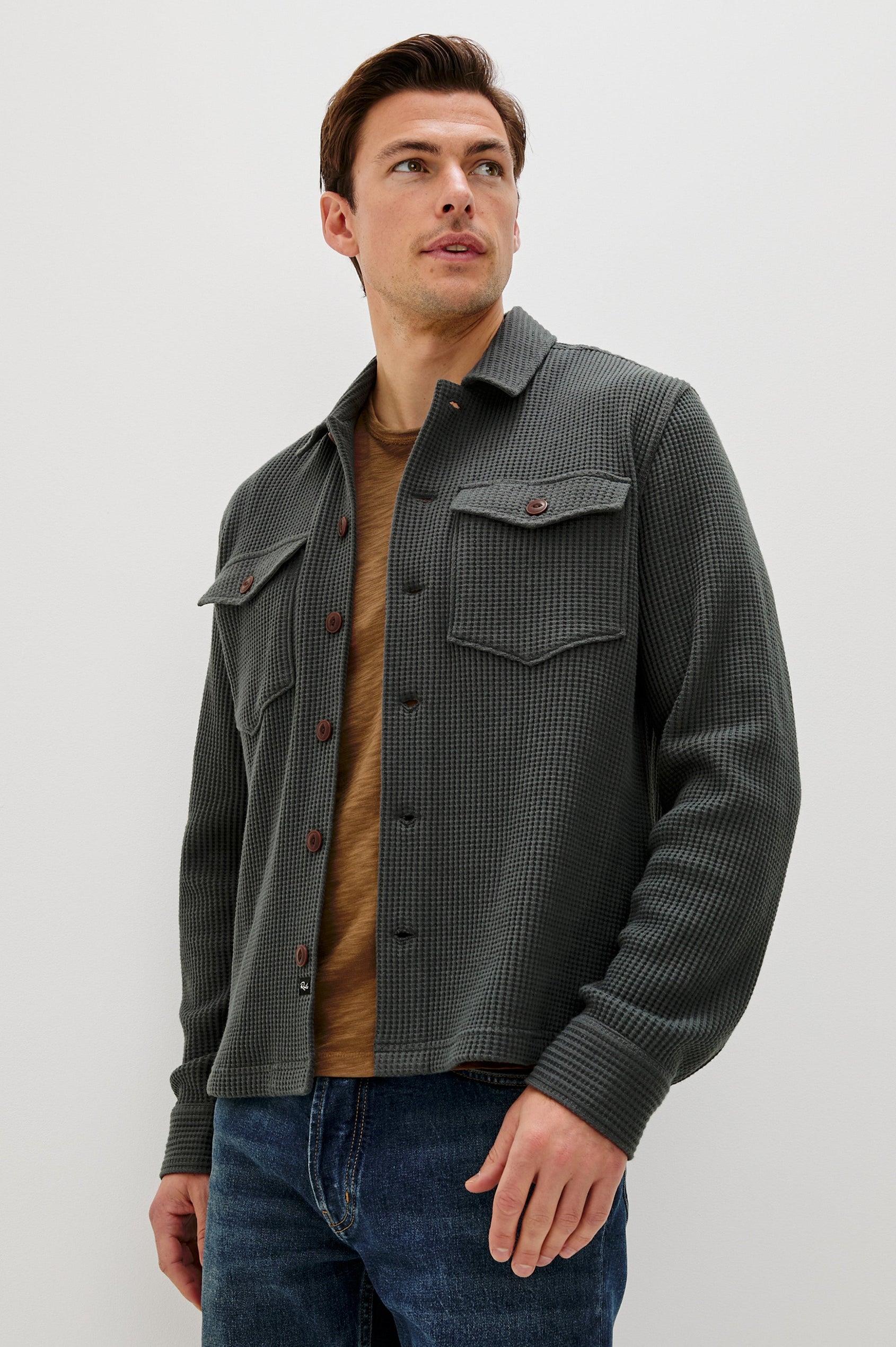 The Wells is a collared button front shirt jacket with contrast brown buttons and two chest pockets in Ink colorway. Front view featured on model.