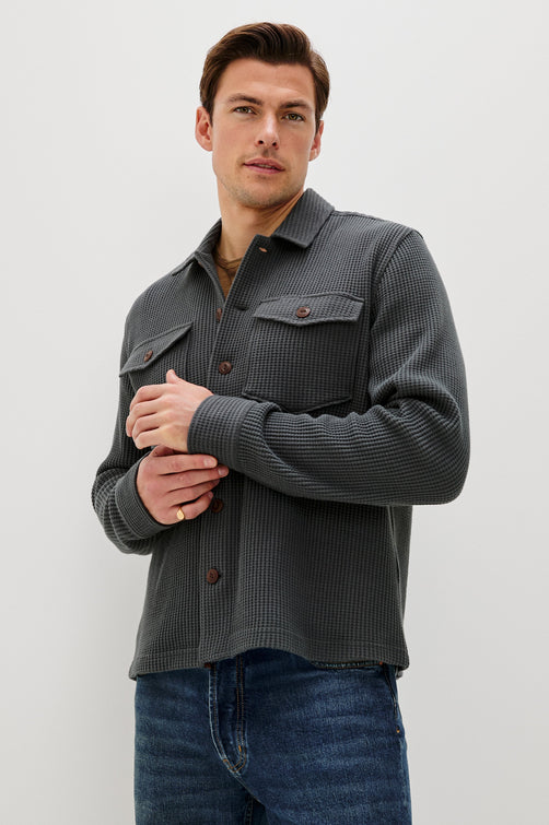 The Wells is a collared button front shirt jacket with contrast brown buttons and two chest pockets in Ink colorway. Front view featured on model.
