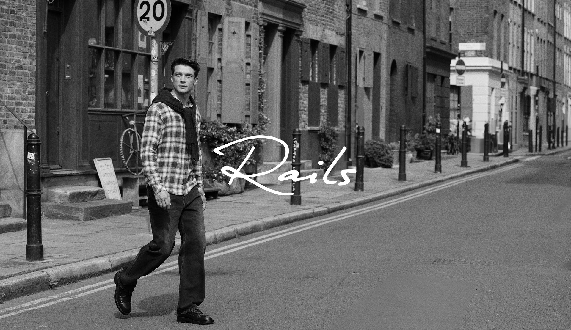 BLACK AND WHITE IMAGE OF MODEL WALKING WEARING LENNOX SHIRT AND CUTLER JEANS