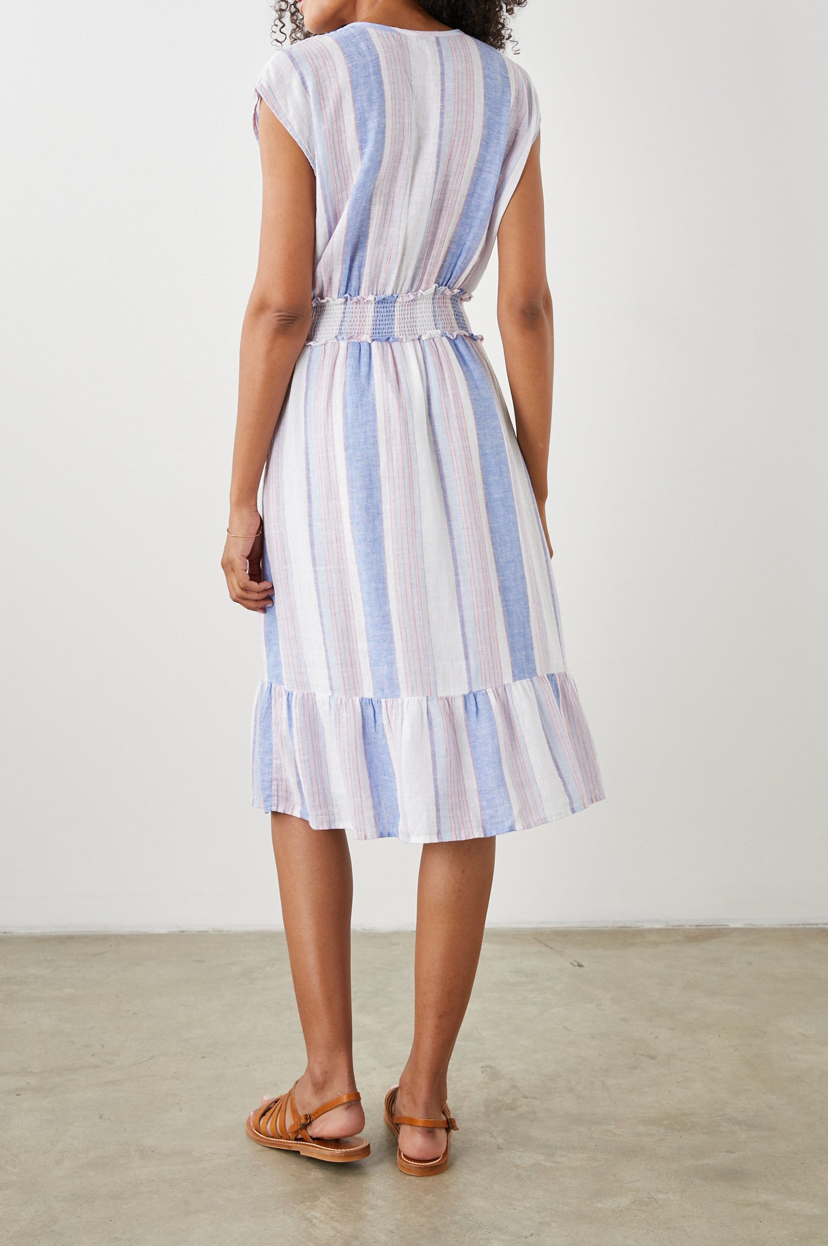 Ashlyn Short Sleeve Midi Dress with a V neck with Ties, a Smocked Waist and a Ruffle Tier at the Hem in Marini Stripe Colorway, Vertical Stripes in Pink and Blue on White - Back Full Body View Featured on Model