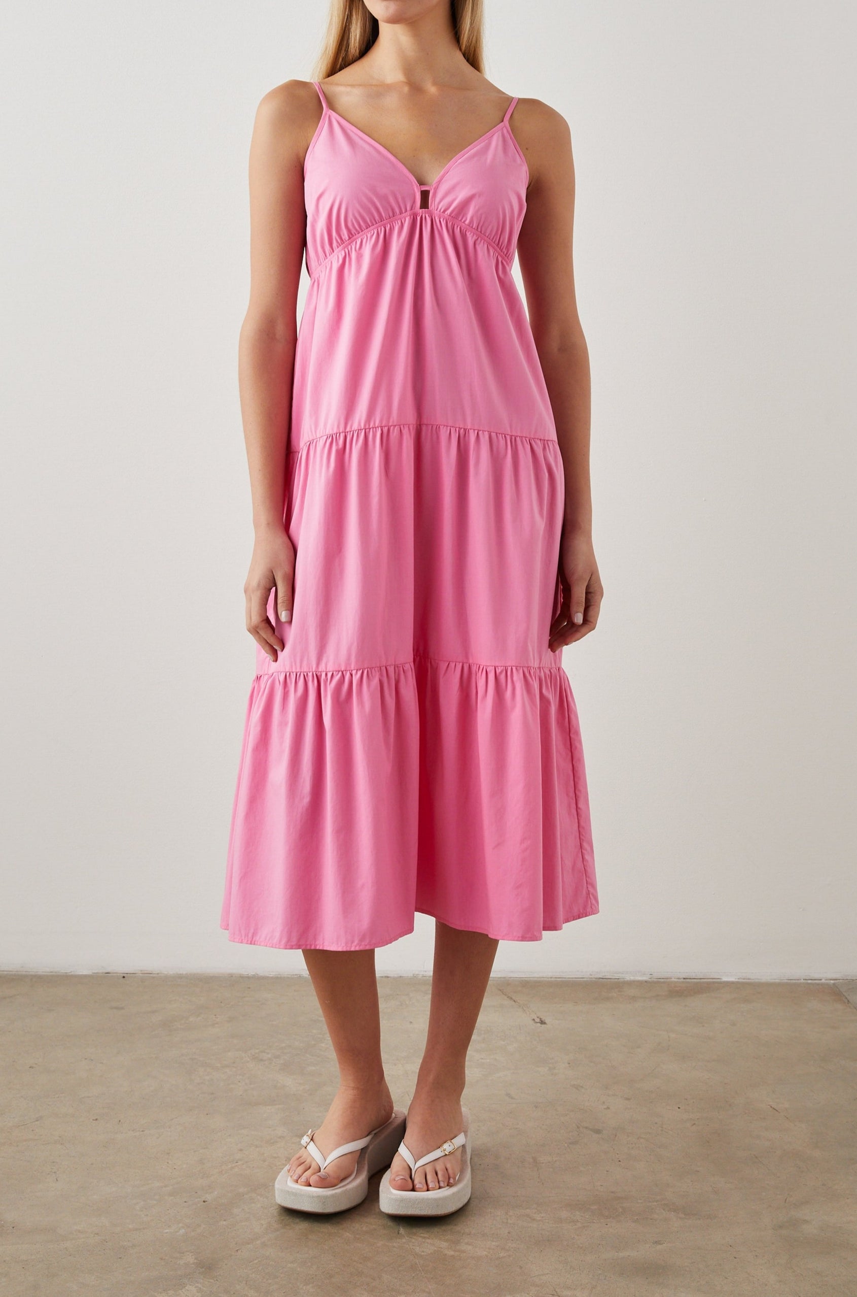 Avril Sleeveless, Tiered Midi Dress with Adjustable Spaghetti Straps, a V Neck with a Cutout and Light Ruching at Each Tier Seam in Hot Pink Colorway - Front Full Body View Featured on Model