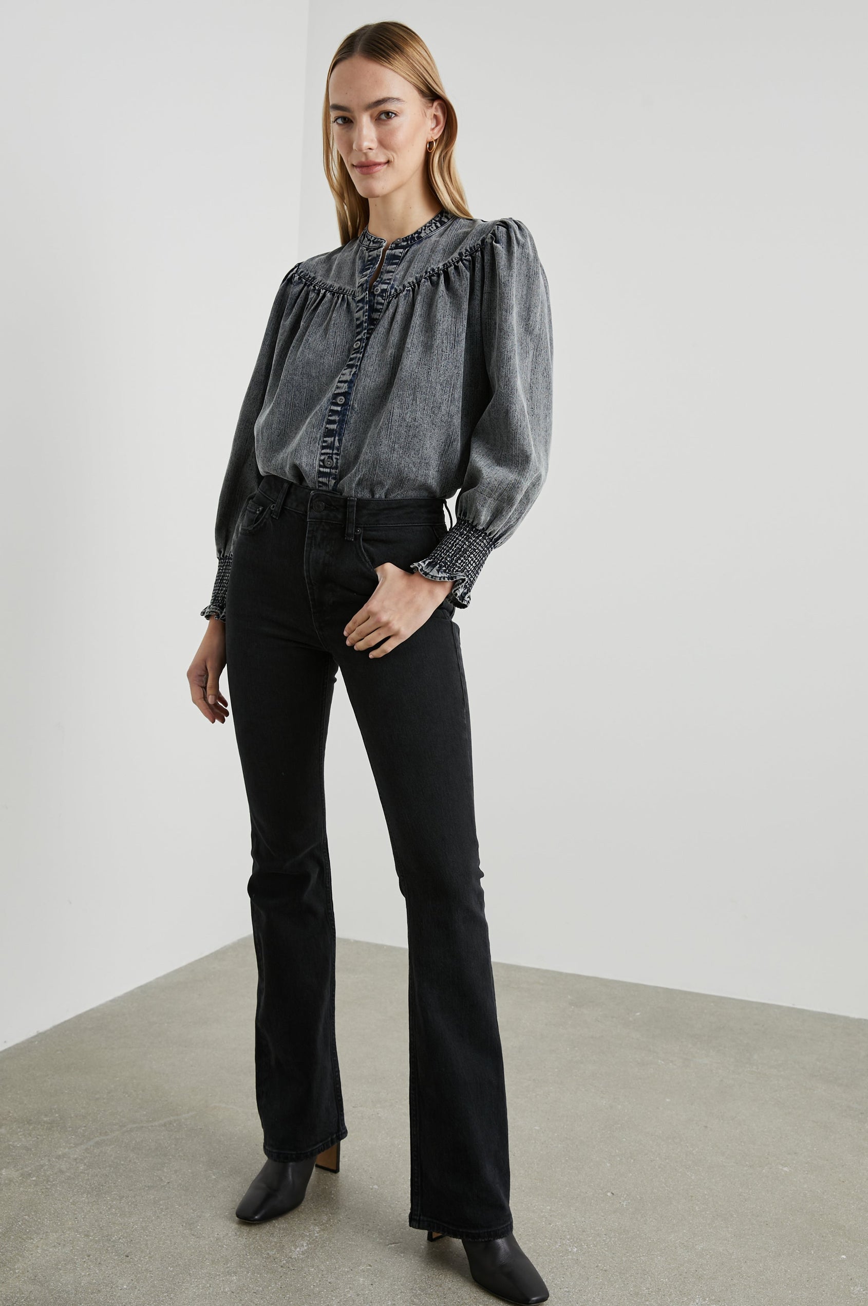 Daphne Long Sleeve Denim Shirt with Front Button Closure, Shirred and Ruffled Cuffs, and Ruching along the Yoke Seams in Ink Wash Colorway - Front Tucked Full Body View Featured on Model