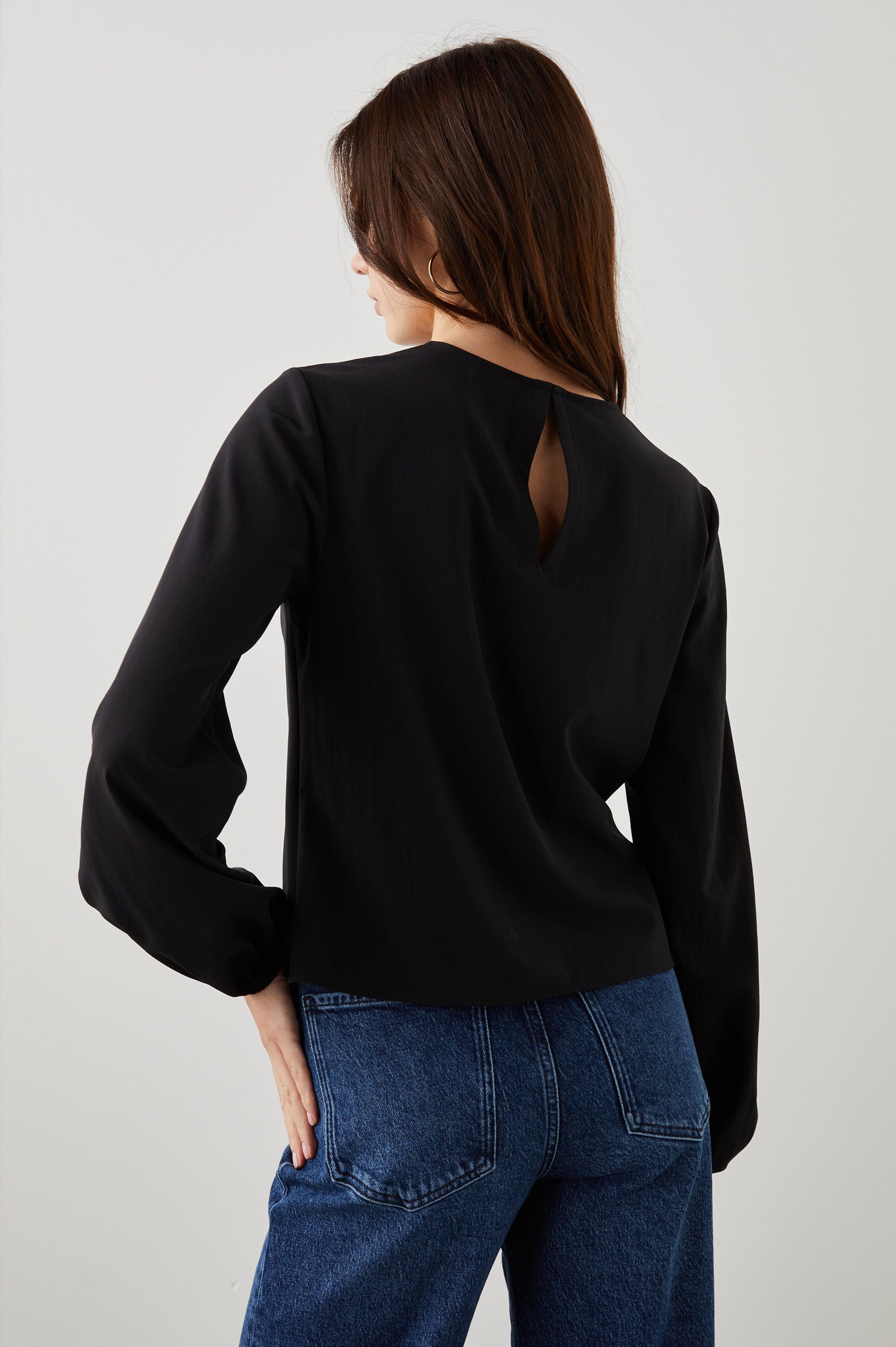 Eli Long-Sleeve Top with Twisted Fabric at the Neckline and a Cutout to the Left and Right of the Twist, a Vertical Seam Down the Front and a Keyhole at the Back in Black Colorway - Back View Featured on Model