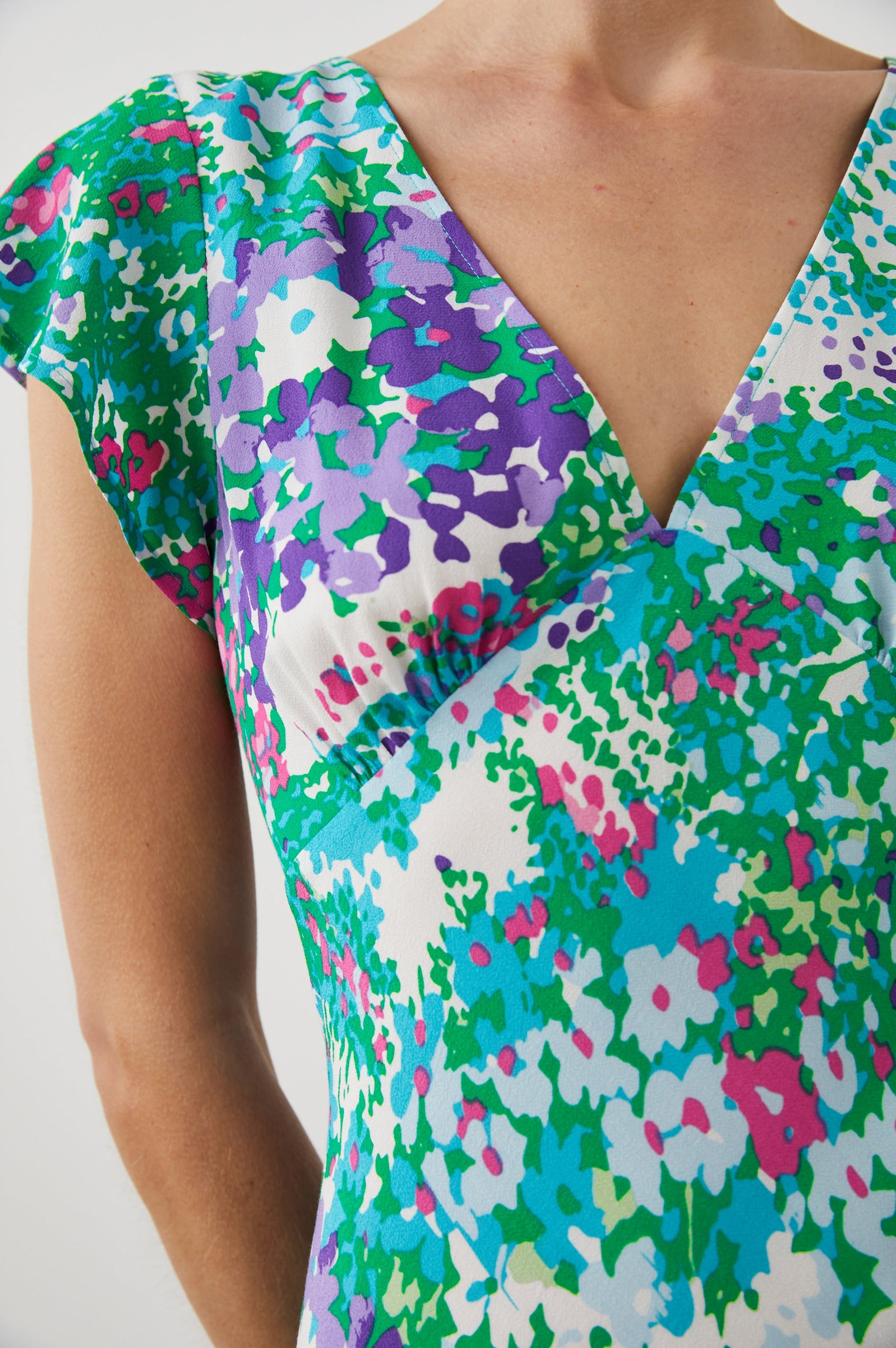 Gigi Short Sleeve Mini Dress with a Deep V Neck, and Flutter Sleeves in Gardenia Floral Colorway, Greens, Blues, Purples, Pink and White - Front View Featured on Model
