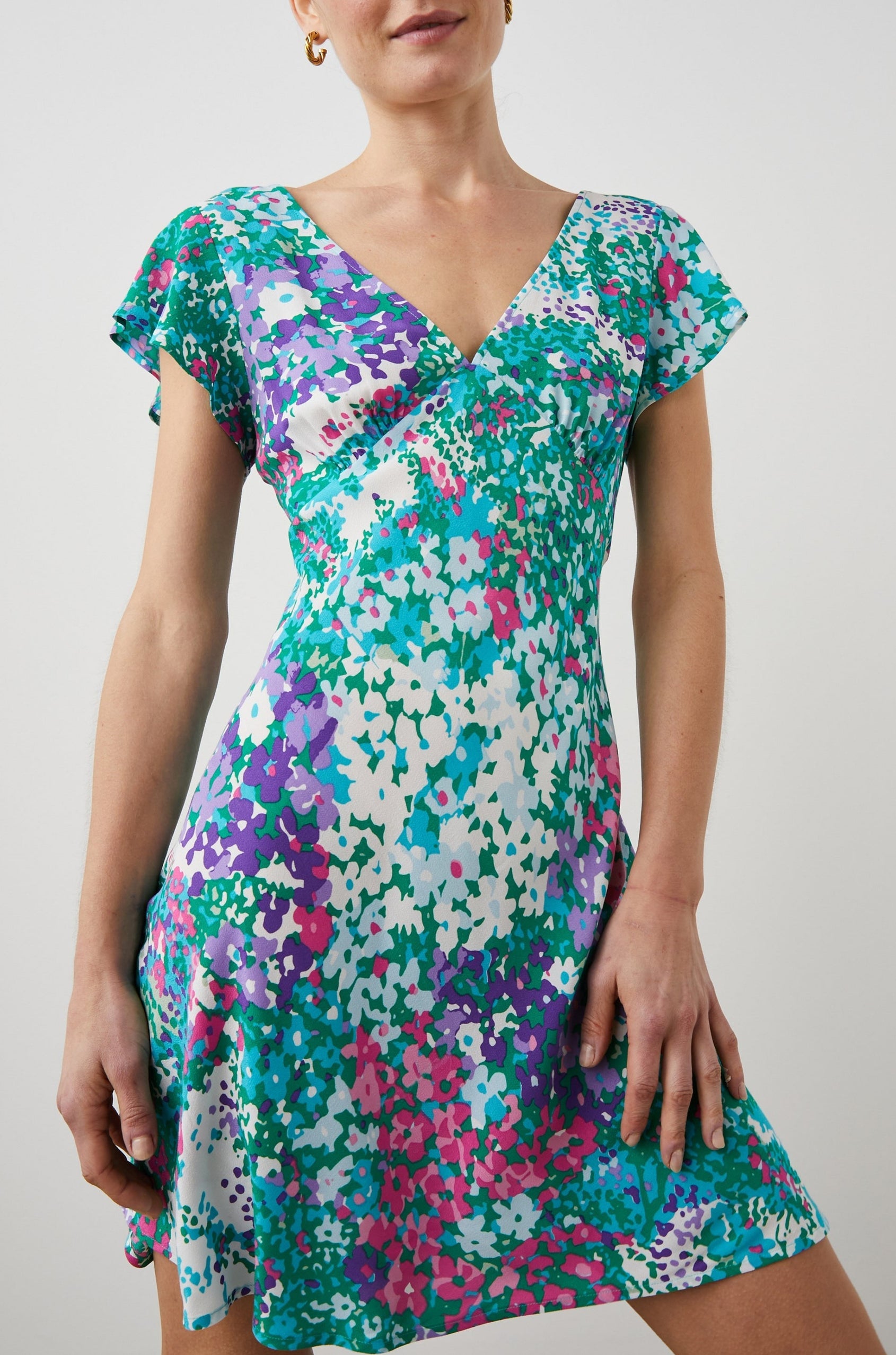 Gigi Short Sleeve Mini Dress with a Deep V Neck, and Flutter Sleeves in Gardenia Floral Colorway, Greens, Blues, Purples, Pink and White - Front View Featured on Model