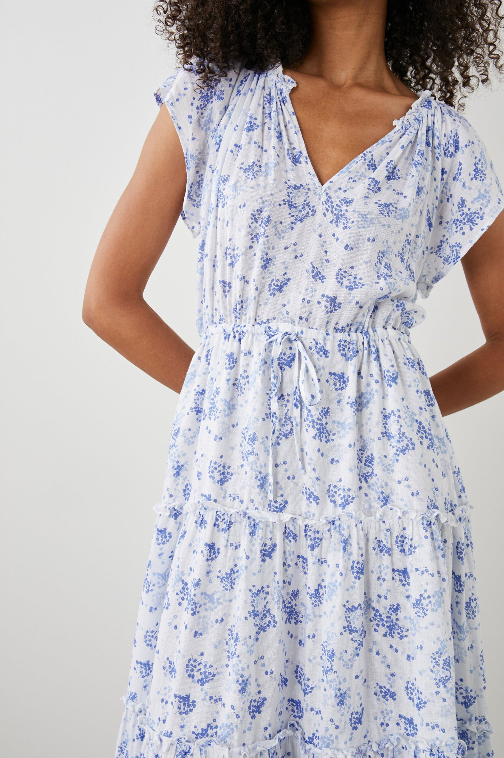 Juni Short Sleeve Midi Dress with a V Neck, Light Ruching along the Neckline, a Drawstring Waist, and a Tiered Skirt in Blue Blossoms Colorway, on White - Front View Featured on Model