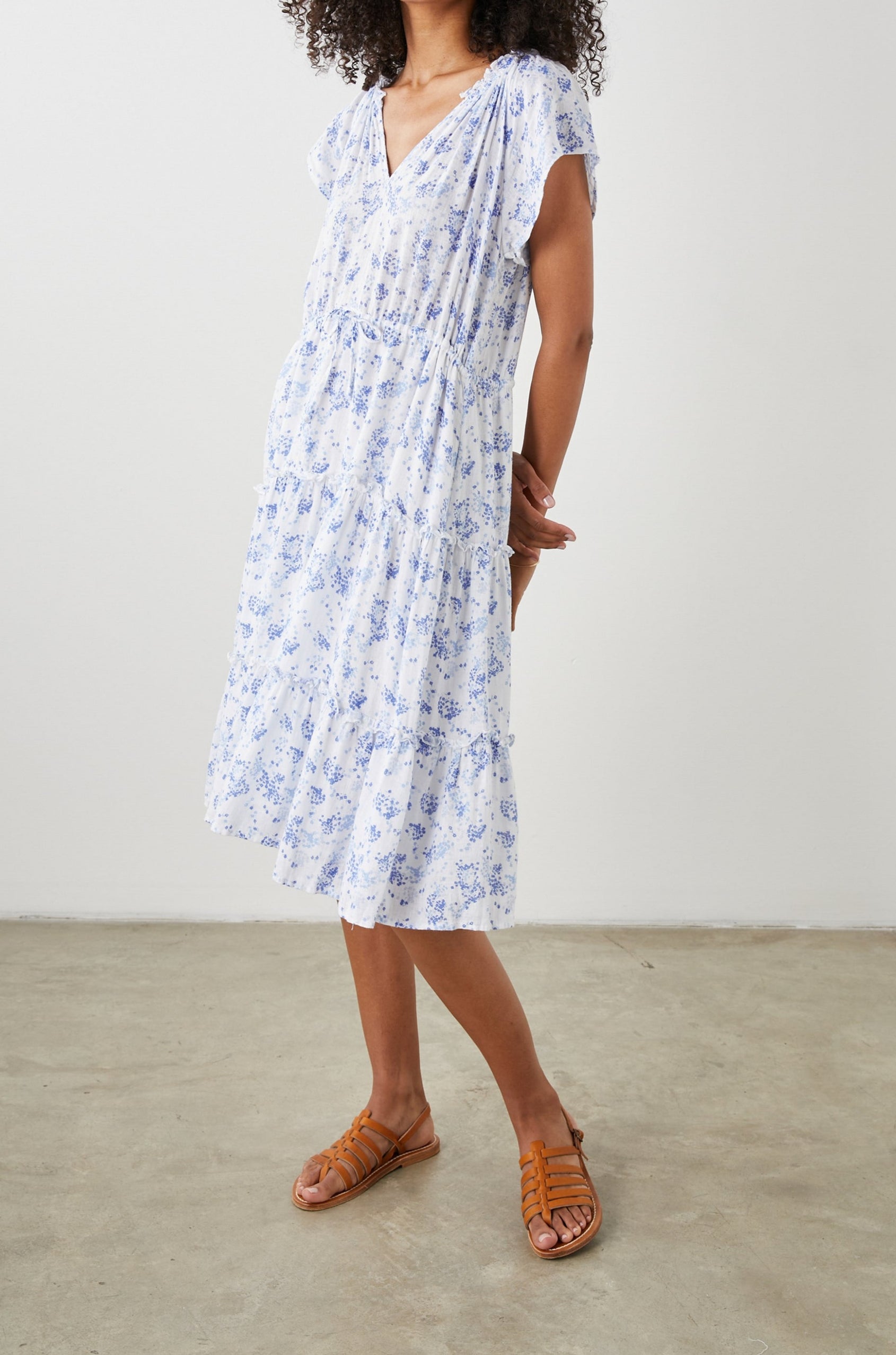 Juni Short Sleeve Midi Dress with a V Neck, Light Ruching along the Neckline, a Drawstring Waist, and a Tiered Skirt in Blue Blossoms Colorway, on White - Side Full Body View Featured on Model