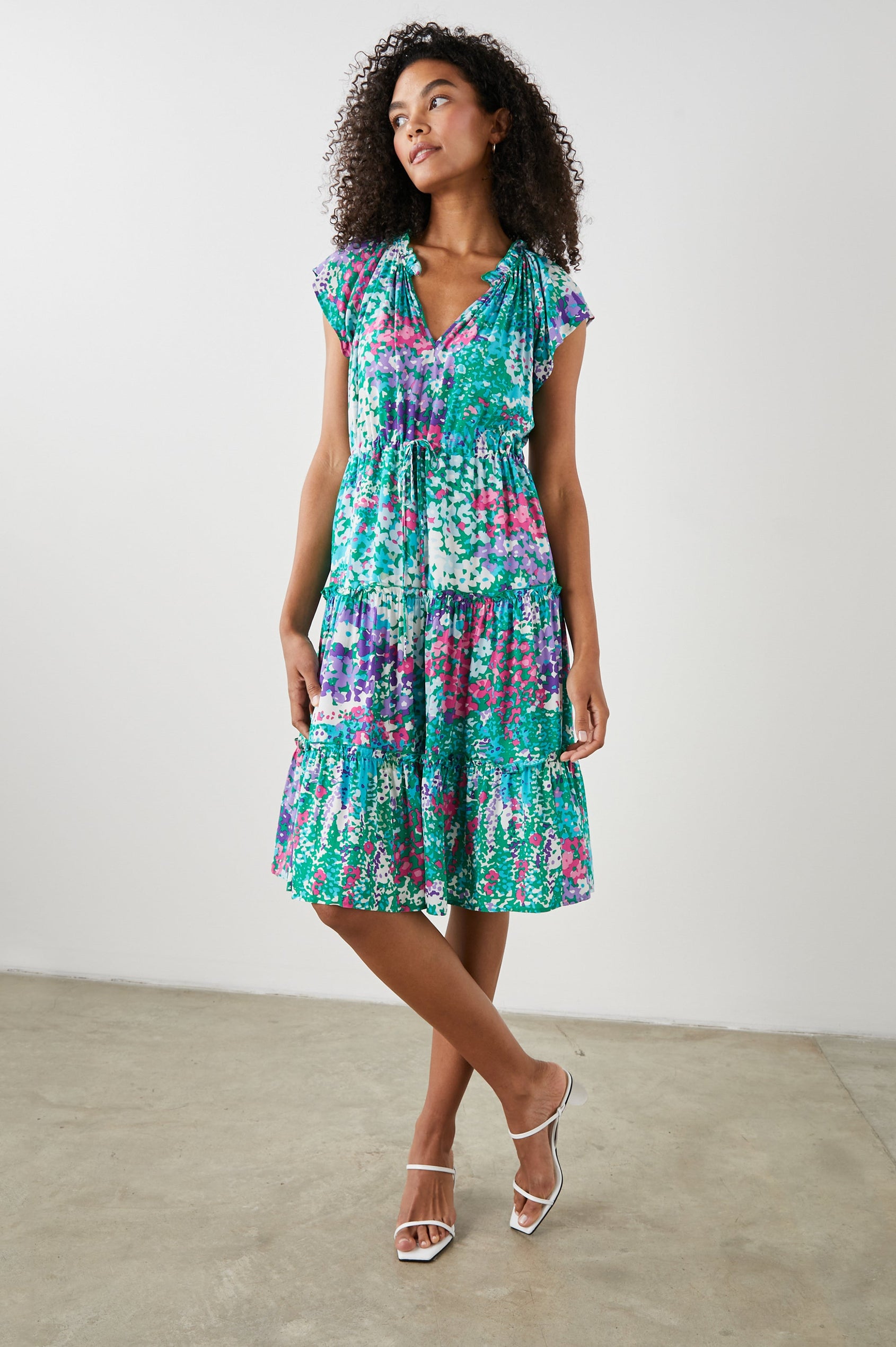 Juni Short Sleeve Midi Dress with a V Neck, Light Ruching along the Neckline, a Drawstring Waist, and a Tiered Skirt in Gardenia Floral Colorway, in Greens, Blues, Purples, Pinks and White - Front Full Body View Featured on Model