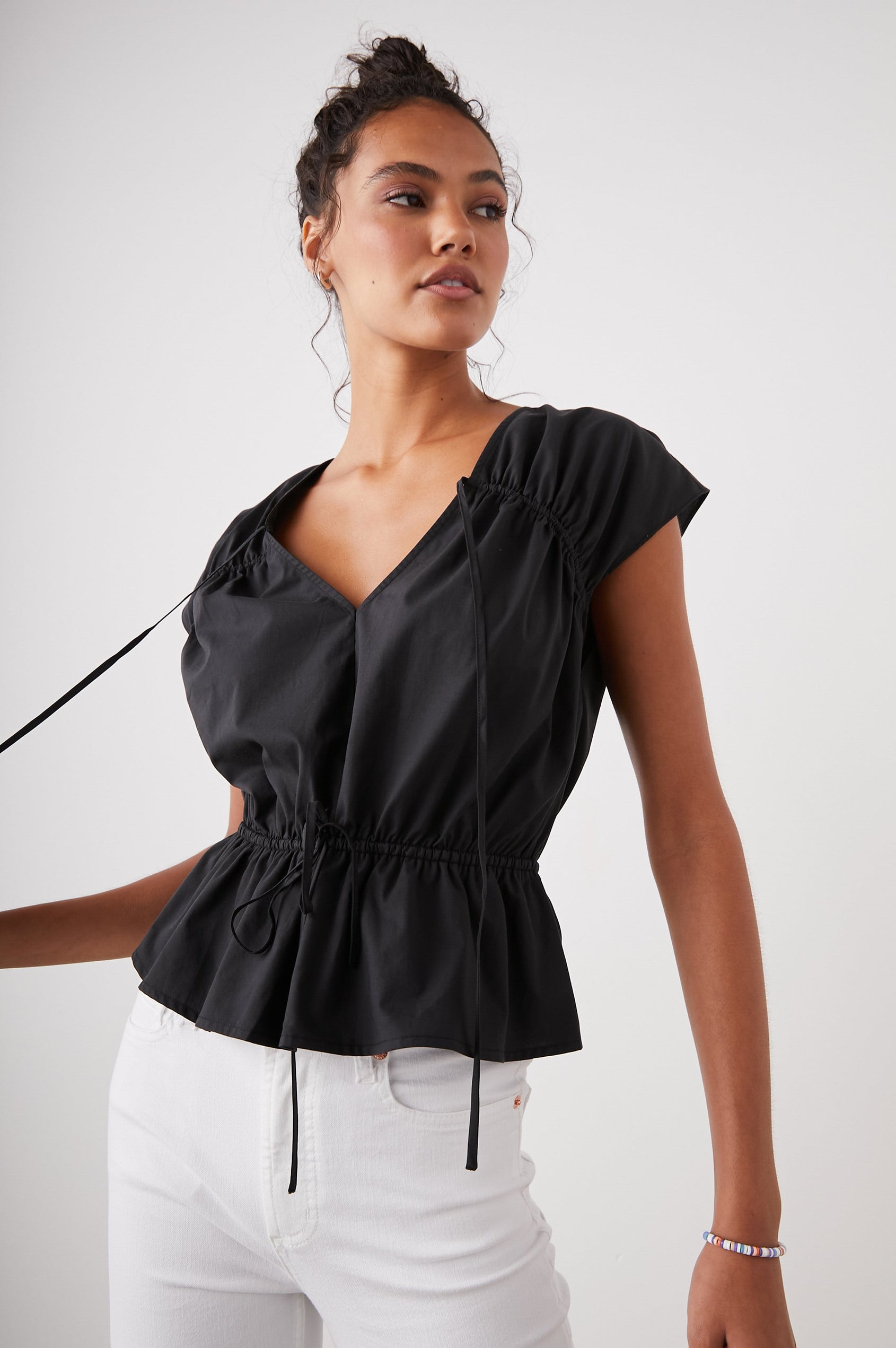 Savi Short-Sleeve Top with a V Neck, Cap Sleeves, a Drawstring From Each Sleeve Shoulder to the Neckline and a Drawstring at the Waist in Black Colorway - Front View Featured on Model
