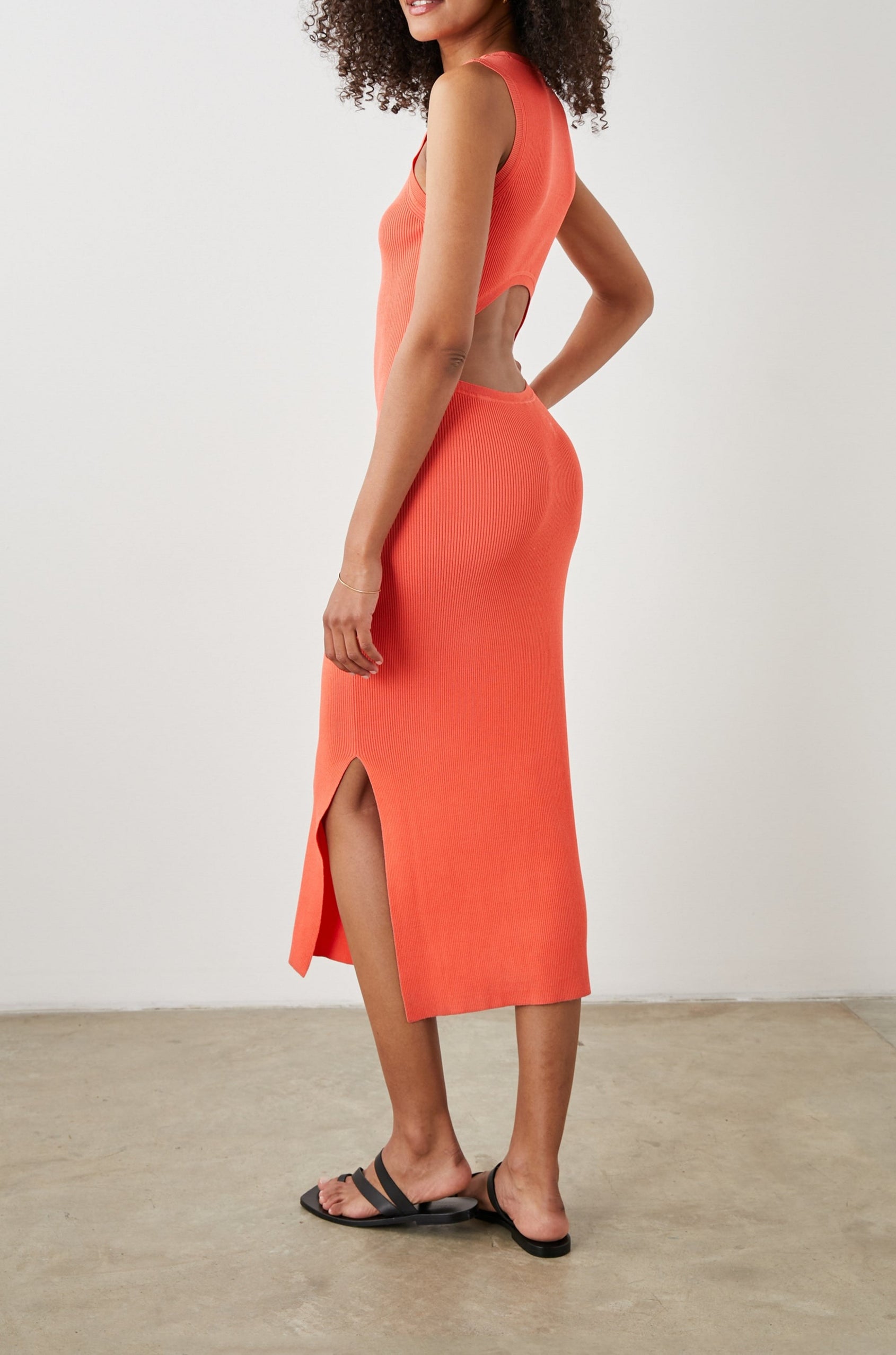 Syd Ribbed, Sleeveless Midi Dress with Wide Shoulder Straps, a Side Slit, and a Cutout that Spans the Lower Back in Black Colorway - Side Full Body View Featured on Model