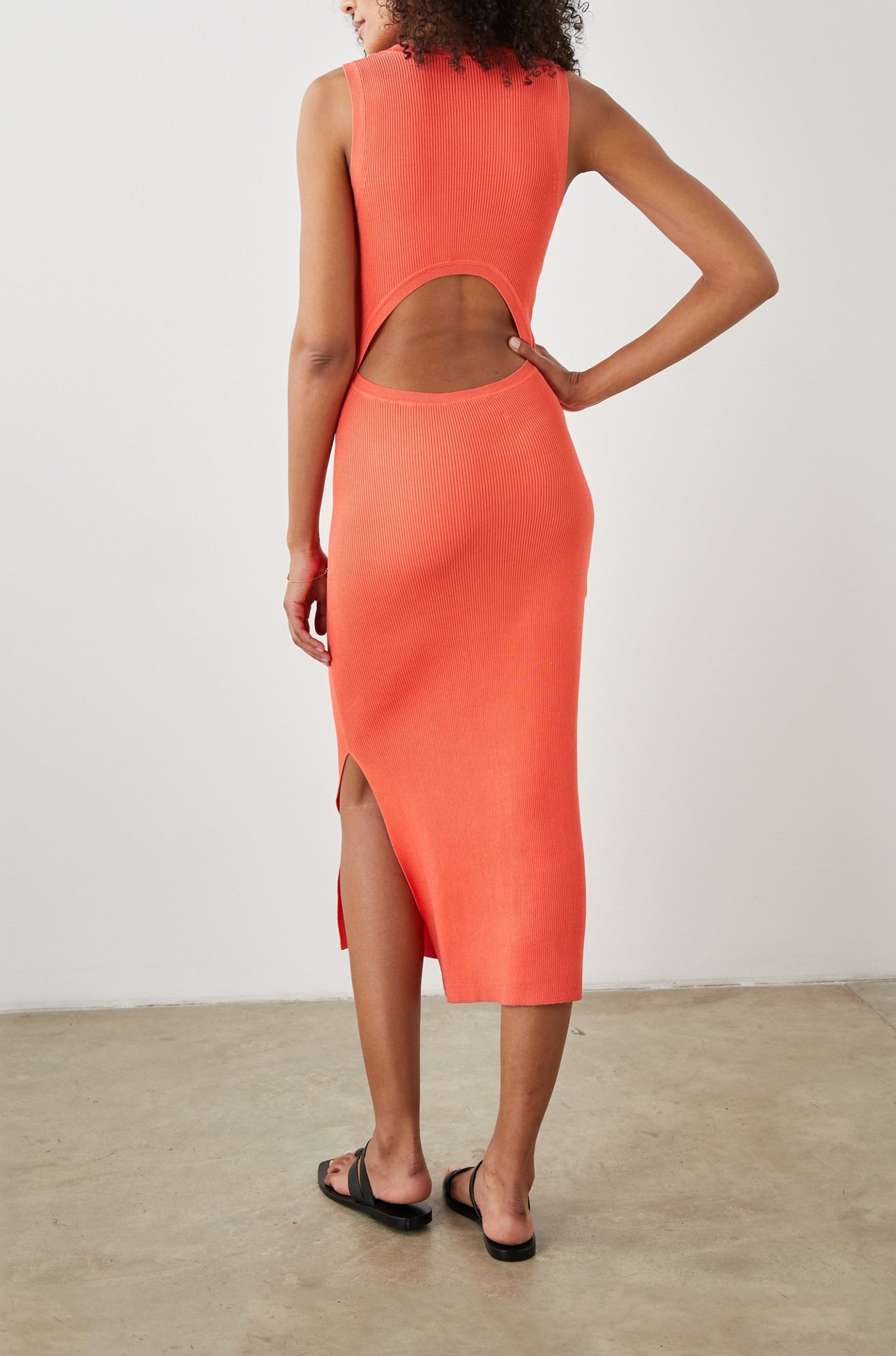 Syd Ribbed, Sleeveless Midi Dress with Wide Shoulder Straps, a Side Slit, and a Cutout that Spans the Lower Back in Black Colorway - Back Full Body View Featured on Model