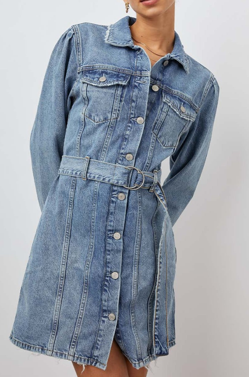 Griffith Long-Sleeve Denim Mini Dress with Buttons Down the Front, a Fabric Double Ring Belt, Two Chest Button Flap Pockets, Frayed Trim and Vertical Seams Down the Front in Indigo Charm Colorway - Front View Featured on Model