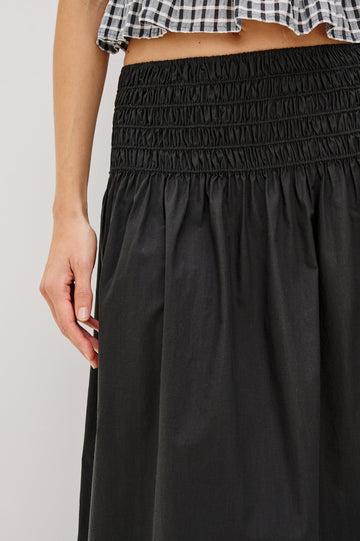 Alessa Midi Skirt with a Wide Elastic Gathered Waistband in Black Colorway. Front View Shown on Model.