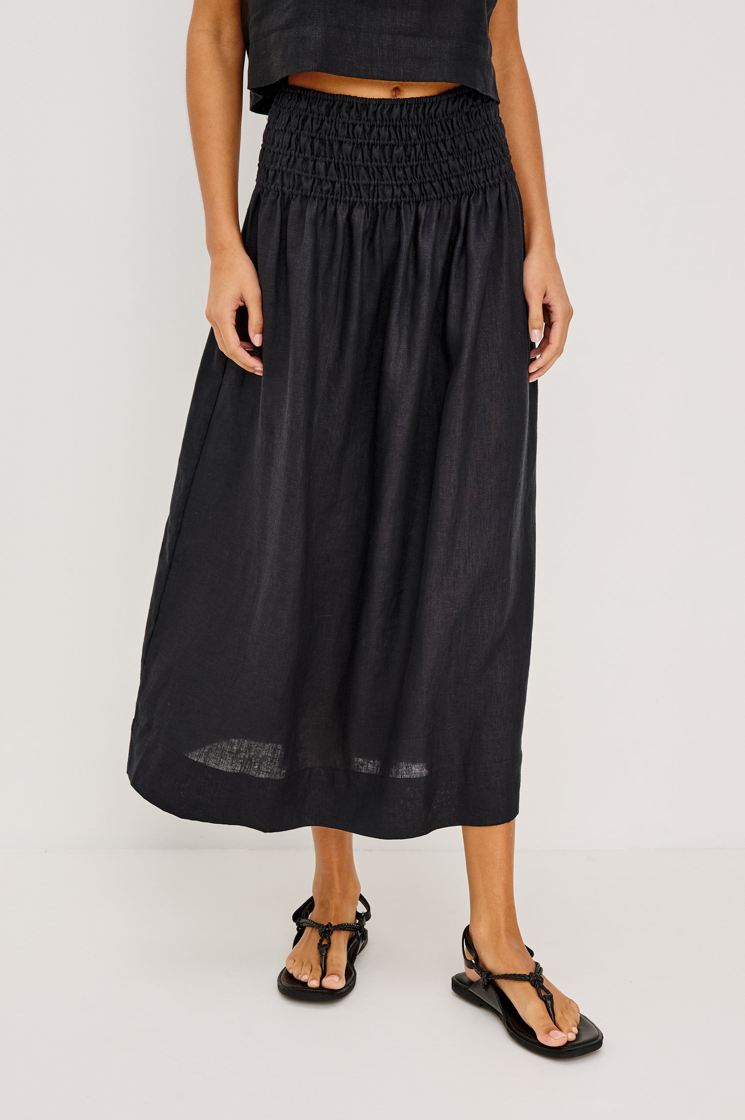 Alessa Midi Skirt in Heavy Linen With Wide Smocked Waistband and A-Line Silhouette in Black Linen Colorway - Lower Body Front View Featured on Model