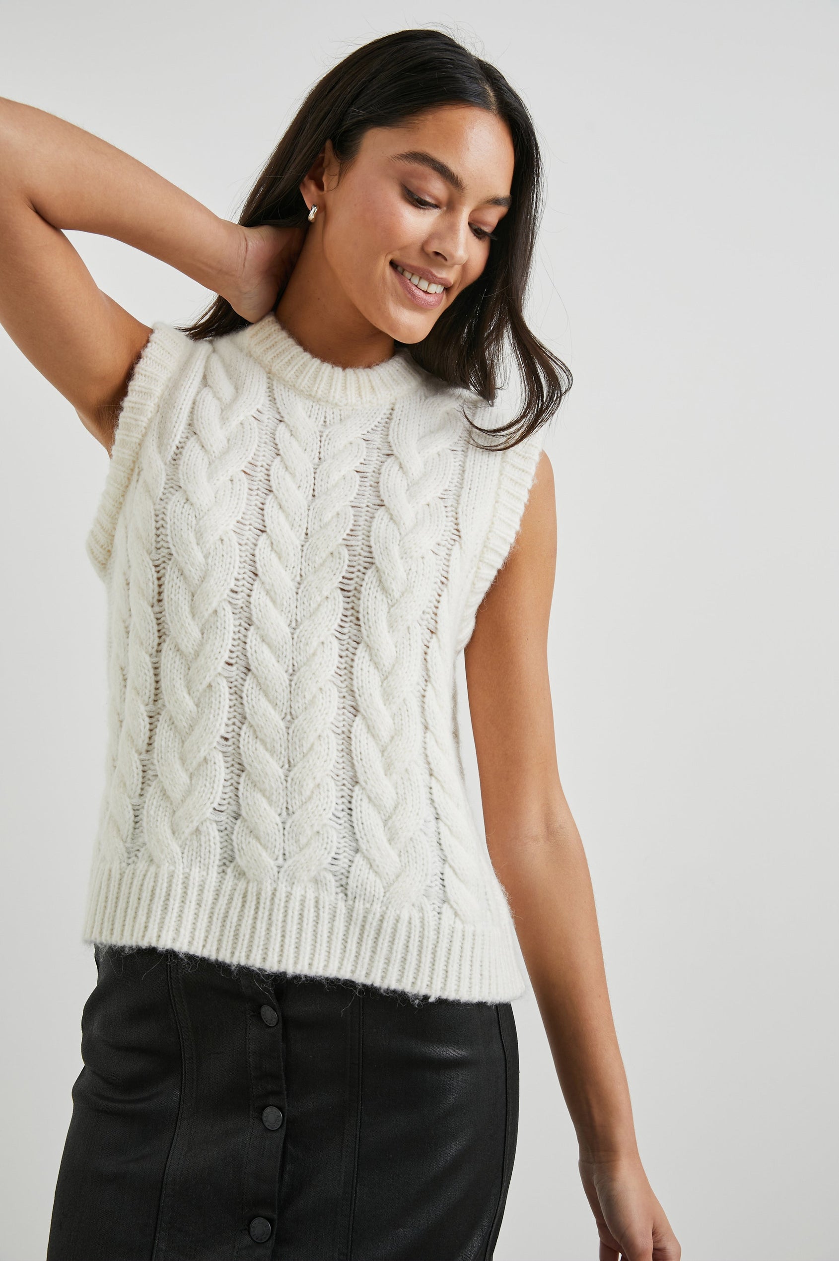 Alexis Sleeveless Cable Knit Sweater Vest with a Crew Neck and Ribbed Trim in Ivory Colorway - Front View Featured on Model 
