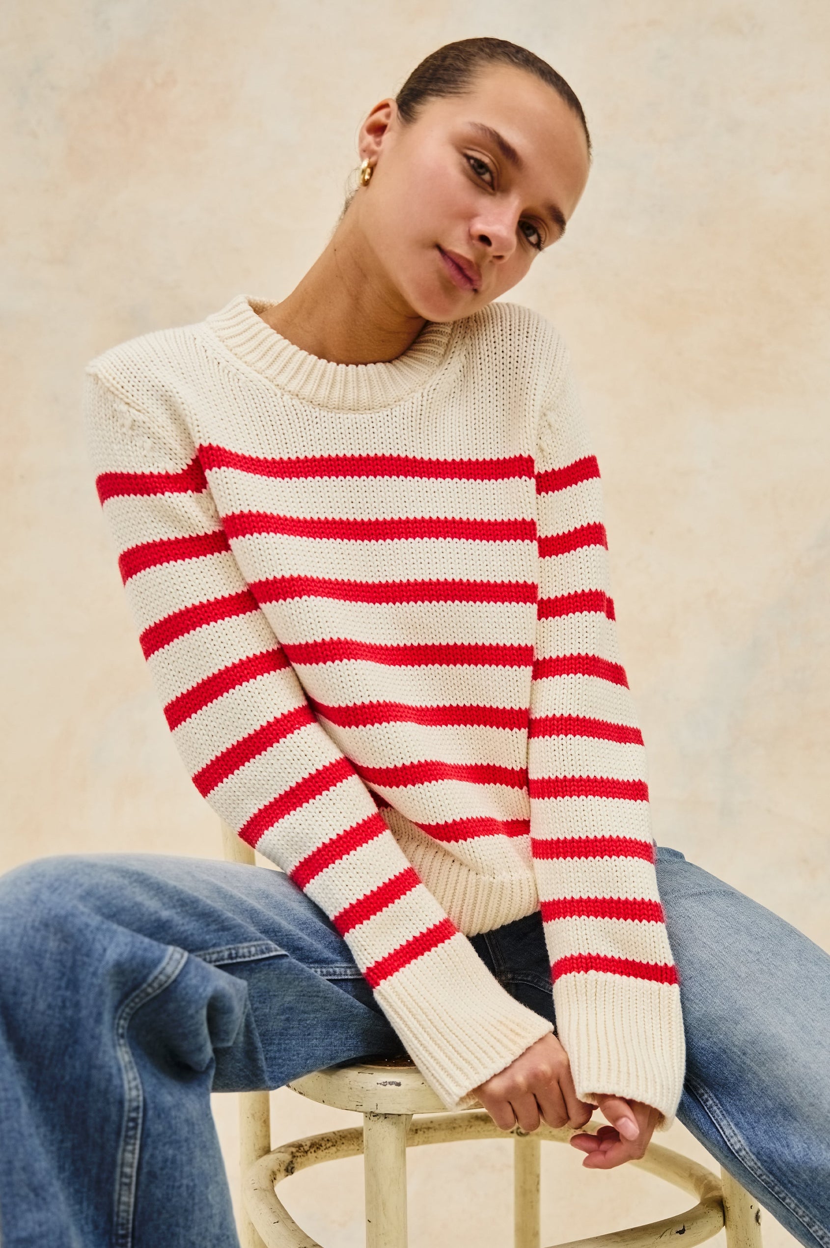 Alise crewneck wool sweater with ribbed detailing on cuffs and collar in Cherry Stripe - stylized front view on model sitting down