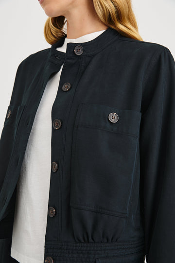 Alma Jacket with Button Closure, Mandarin Collar, Two Large Chest Button Patch Pockets and a Drawcord at the Hem in Black Colorway - Front View Featured on Model