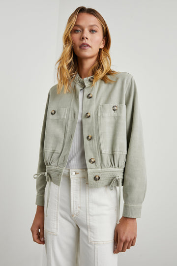 Alma Jacket with Button Closure, Mandarin Collar, Two Large Chest Button Patch Pockets and a Drawcord at the Hem in Sage Colorway - Front View Featured on Model